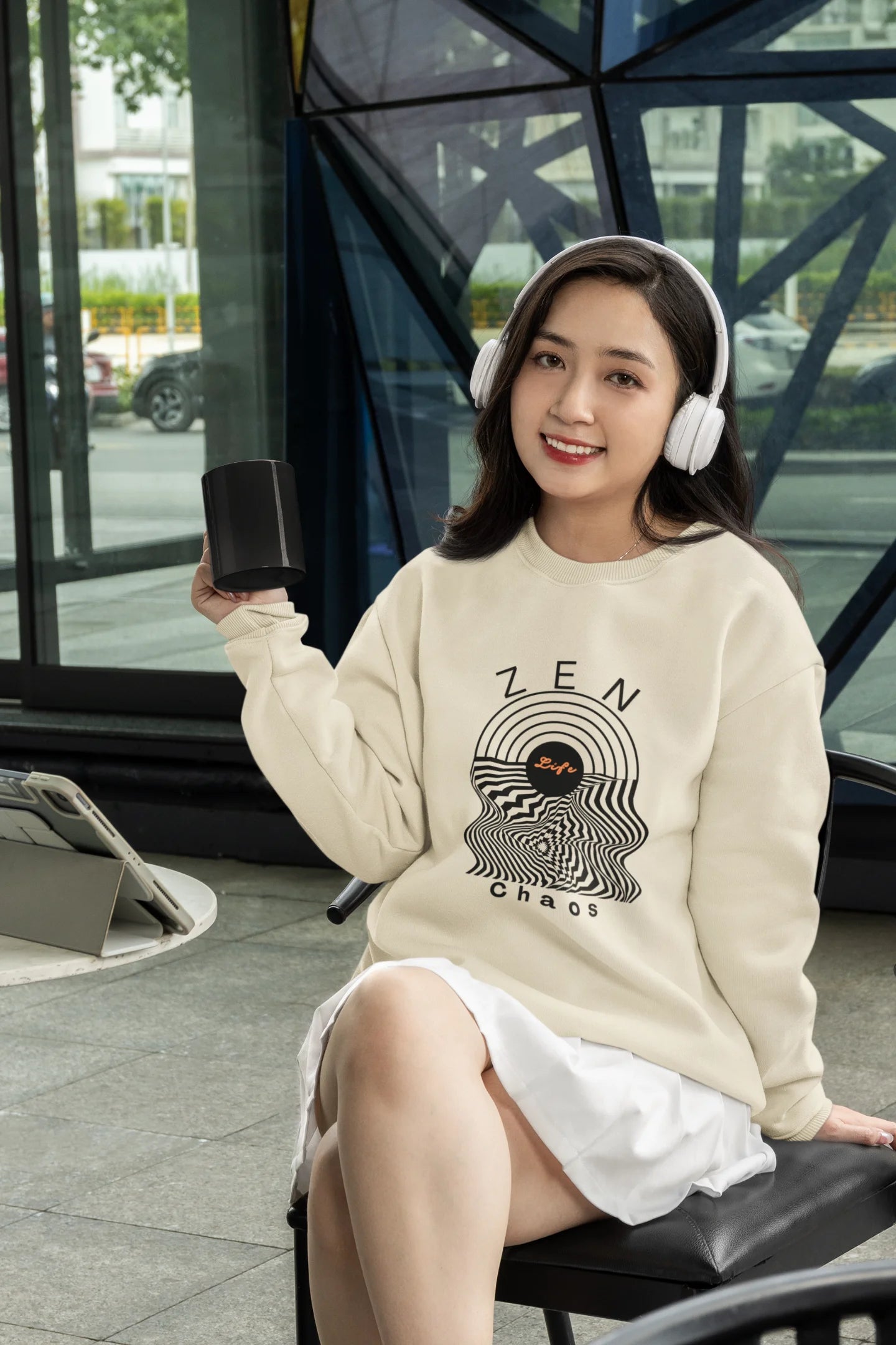 3rd front view of a female model wearing an cream sweatshirt featuring an aesthetic design of a setting sun and crashing waves with the text "Zen & Chaos" above it. Ideal for those who love philosophical themes and visually striking clothing.