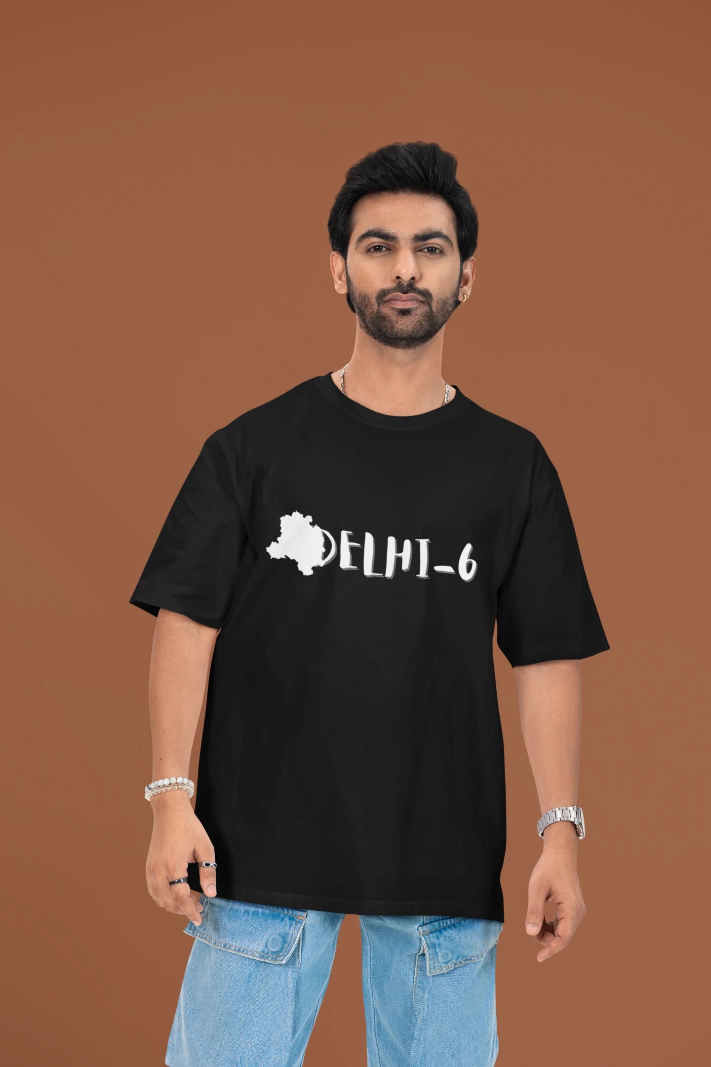 Another front view of a male model wearing a black oversized t-shirt featuring a design incorporating the Red Fort and elements representing the city of Delhi, inspired by the Hindi film Delhi 6.