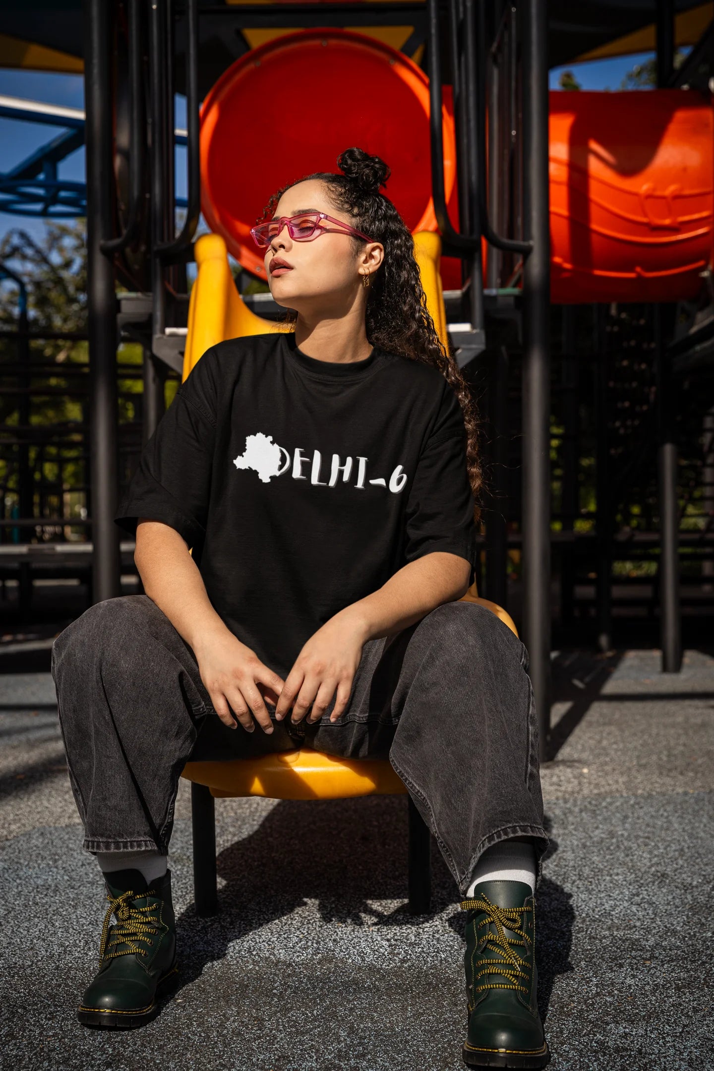 Side view of a female model wearing a black oversized t-shirt featuring a design incorporating the Red Fort and elements representing the city of Delhi, inspired by the Hindi film Delhi 6.