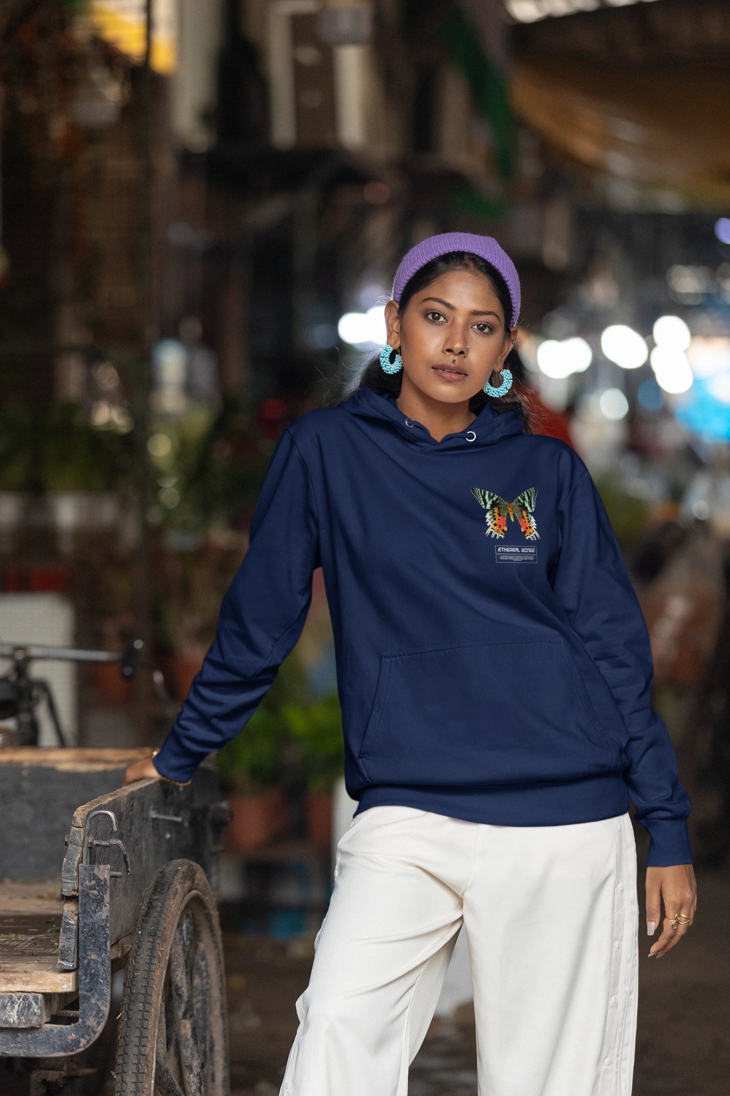 Fifth front view of a female model wearing a navy blue hoodie with a glowing butterfly design, symbolizing the ethereal beauty of nature.