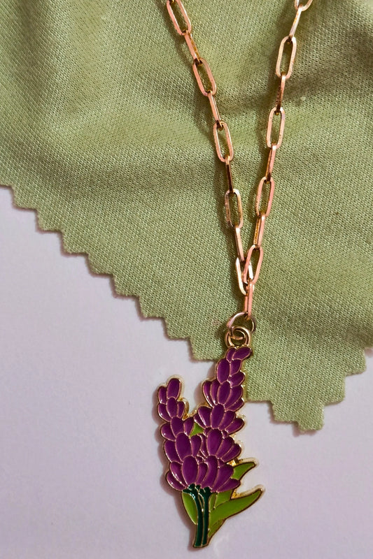 First view of a gold chain necklace with a small pendant shaped like a Snapdragon flower.