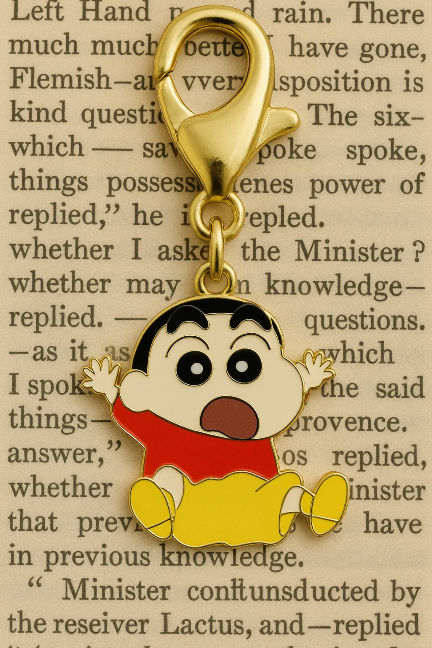 A keychain featuring a charm of Shinchan jumping in the air with the word "Hurray!" on a page background