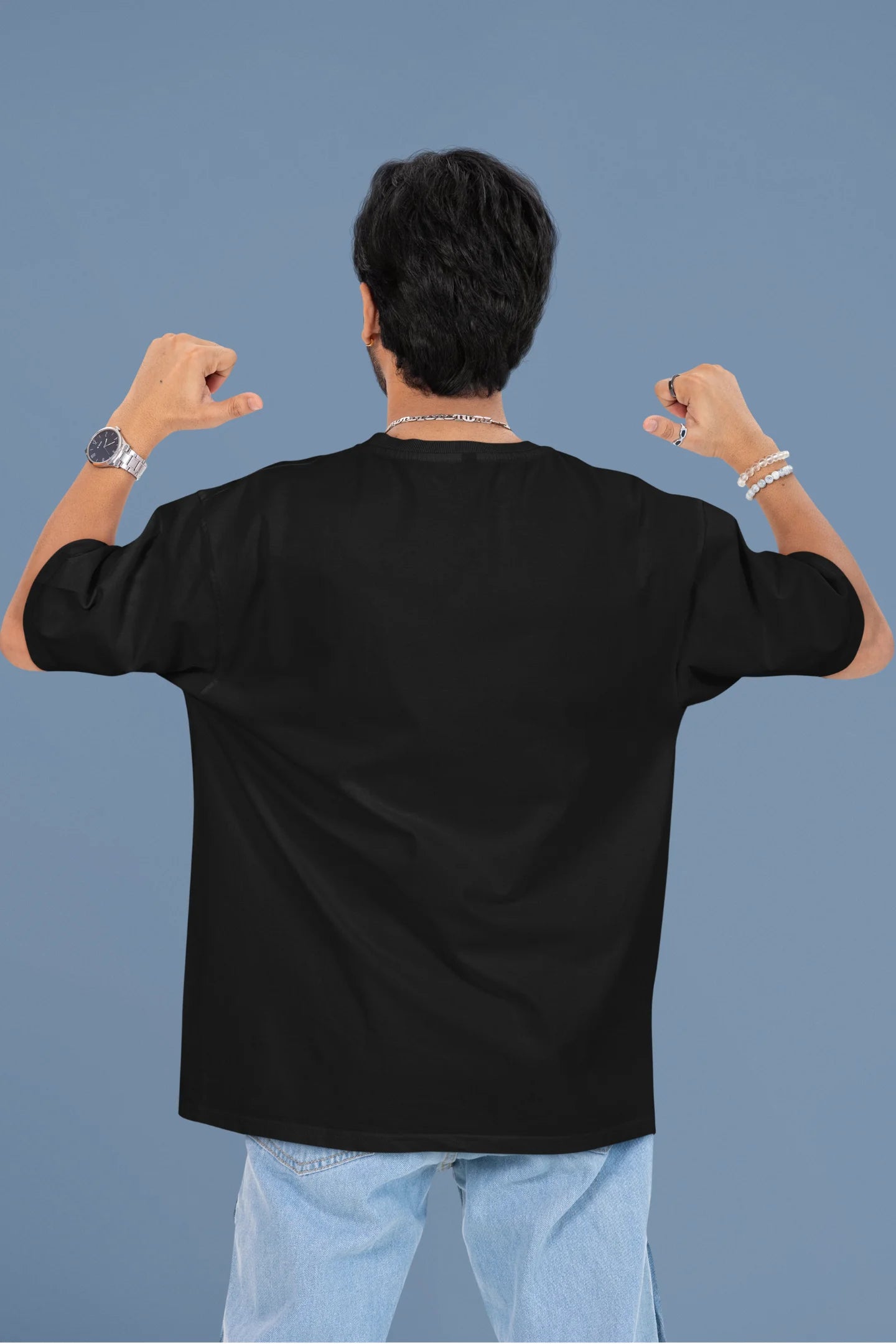 Back image of a male model wearing a black oversized t-shirt with the text "Cold Outside Like My Heart" and a design of a skeleton drinking champagne.