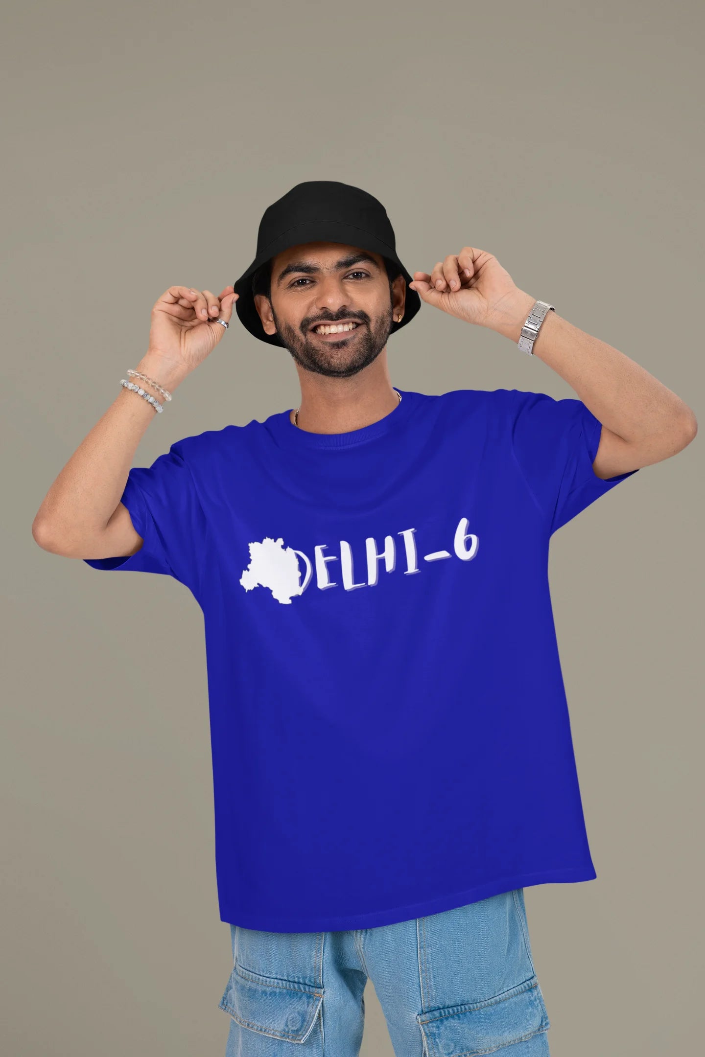 Front view of a male model wearing a royal blue oversized t-shirt featuring a design incorporating the Red Fort and elements representing the city of Delhi, inspired by the Hindi film Delhi 6.