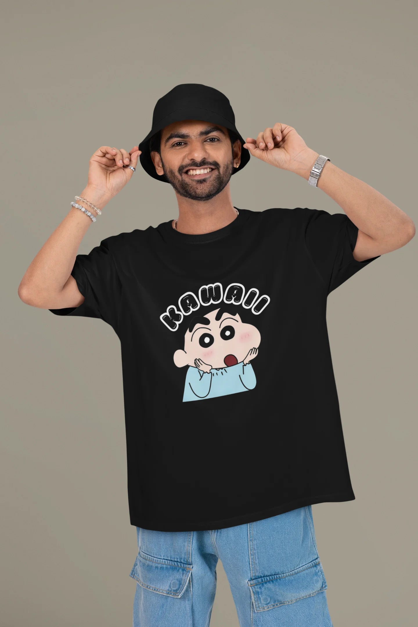 First front view of a male model wearin a black oversized t-shirt featuring Shinchan looking amazed and saying "Kawaii."