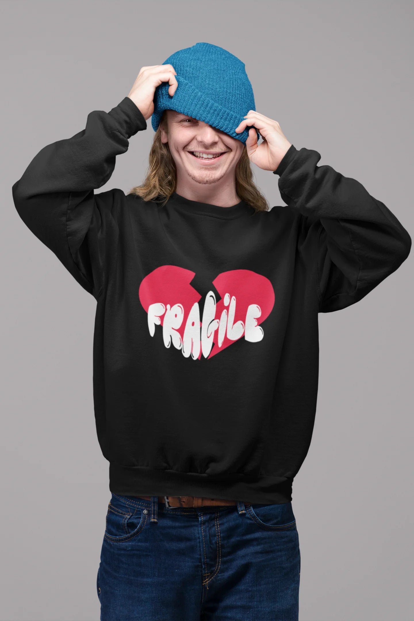 First front view of a male model wearing a black sweatshirt with a broken heart design and the word "Fragile" in melting text.