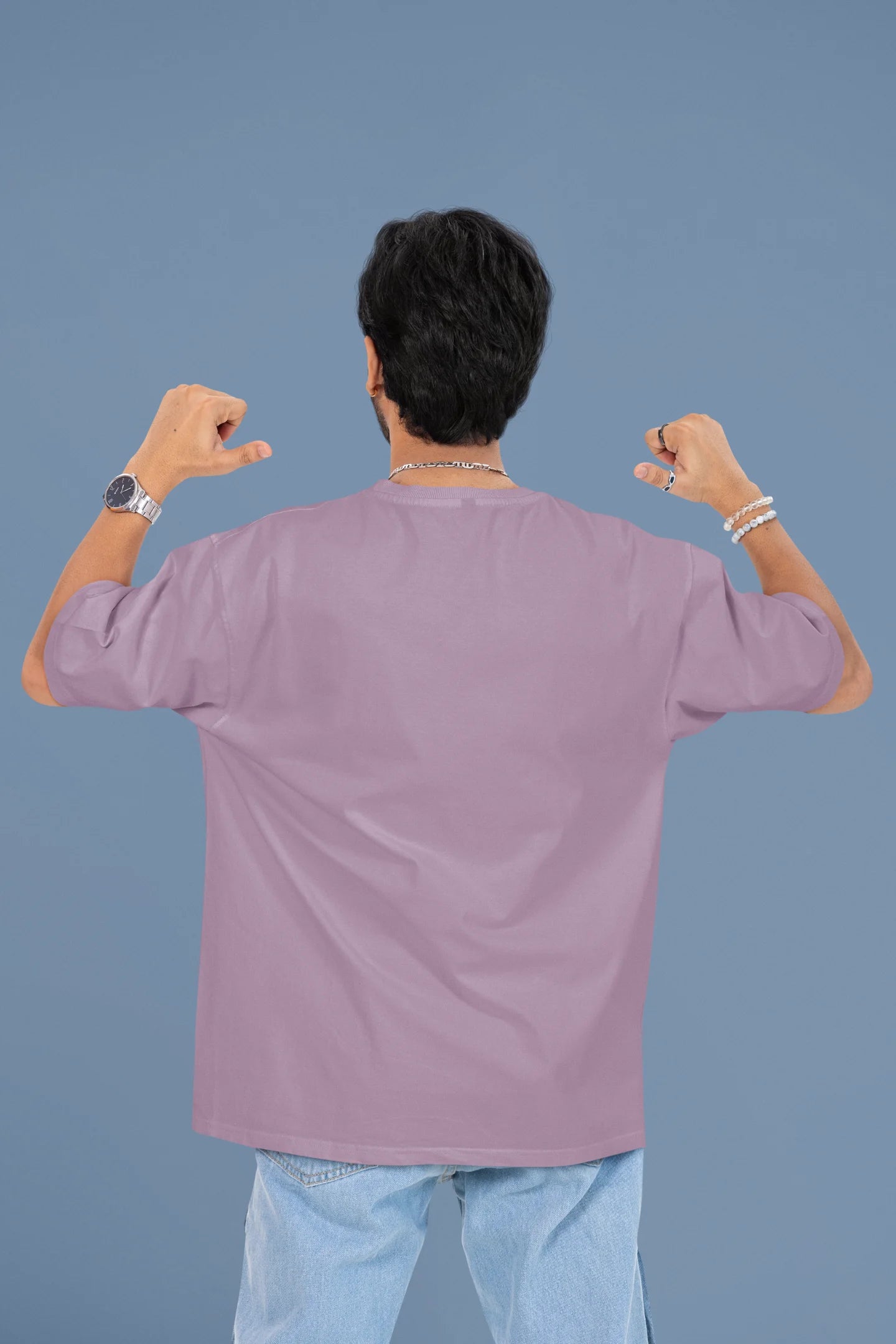 Back image of a male model wearing a dirty purple oversized t-shirt with the text "Cold Outside Like My Heart" and a design of a skeleton drinking champagne.