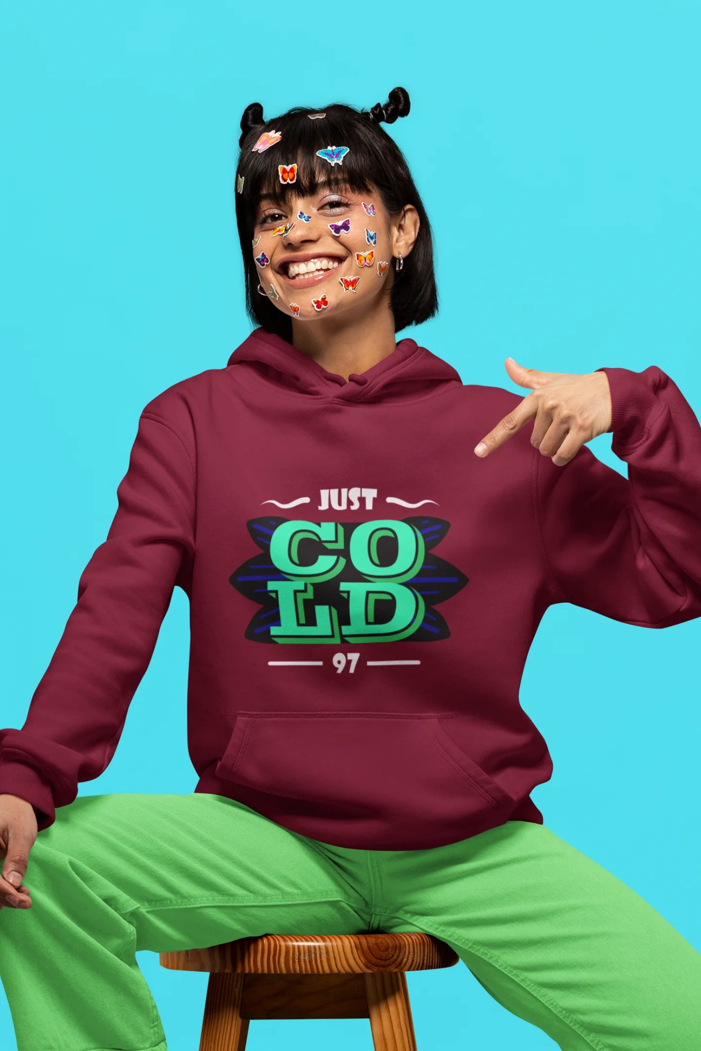5th front view of a female model wearing an maroon sweatshirt with the text "Just Cold" printed on it.