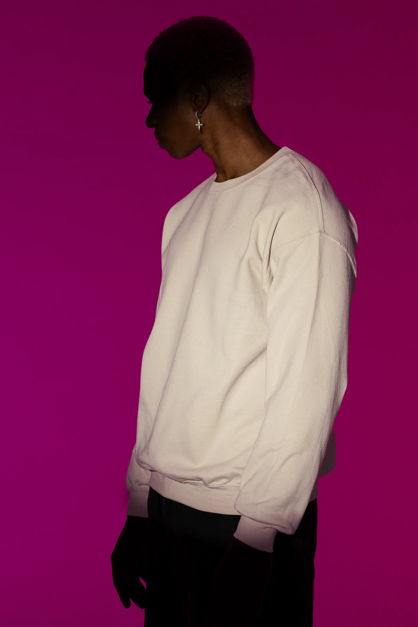 Front view of a male model wearing an cream sweatshirt featuring a detailed illustration of a gray wolf howling at a full moon in a nighttime setting.