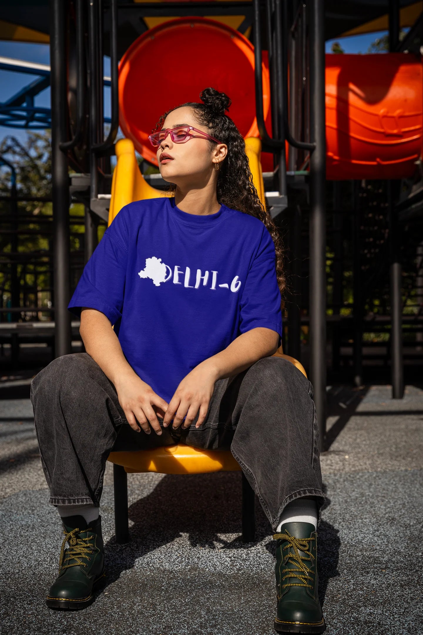 Side view of a female model wearing a royal blue oversized t-shirt featuring a design incorporating the Red Fort and elements representing the city of Delhi, inspired by the Hindi film Delhi 6.