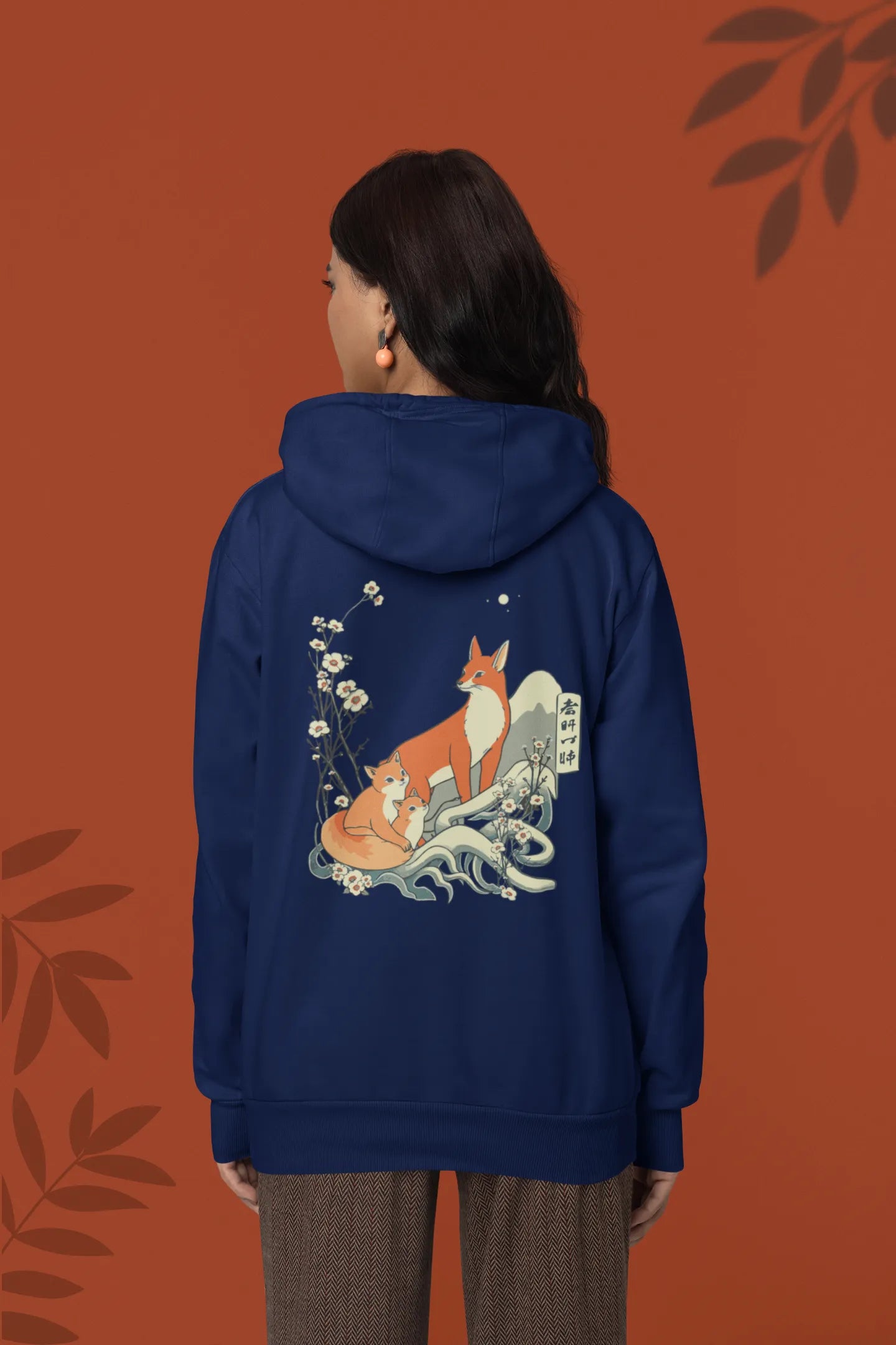 Back view female model wearing a navy blue hoodie with a design of a fox and its cub in a traditional Japanese landscape.