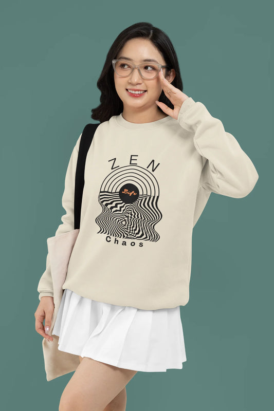 2nd front view of a female model wearing an cream sweatshirt featuring an aesthetic design of a setting sun and crashing waves with the text "Zen & Chaos" above it. Ideal for those who love philosophical themes and visually striking clothing.