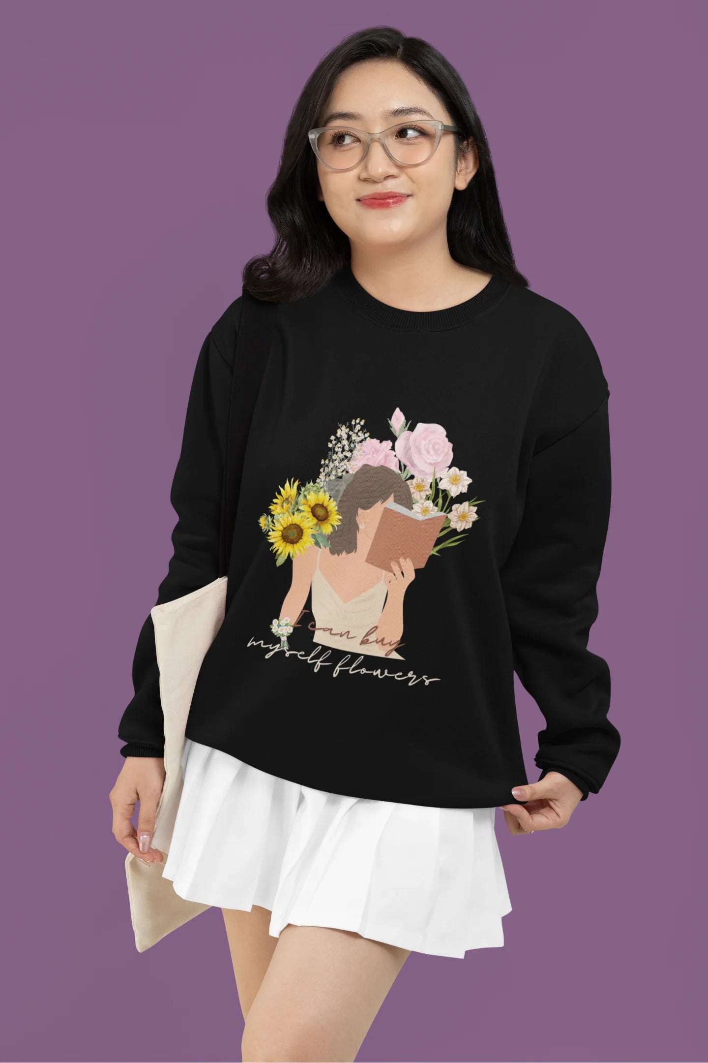 First front view of female model wearing a black sweatshirt with a positive message "Buy Myself Flowers" and a graphic of a smiling woman surrounded by tulips and sunflowers. Ideal for those who love inspirational clothing and floral designs.