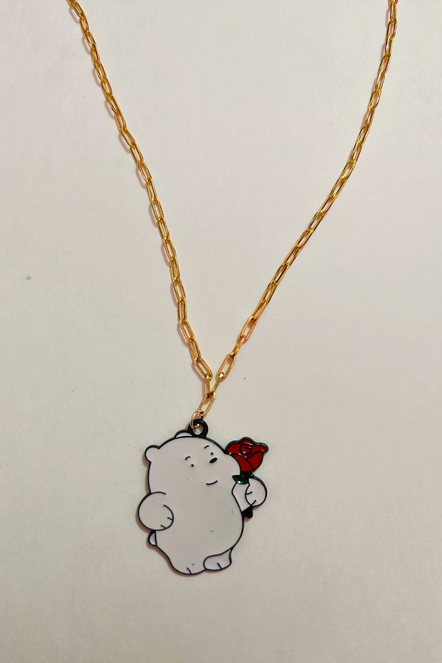 4th view of a gold chain necklace with a small pendant of Ice Bear from a cartoon, holding a rose.