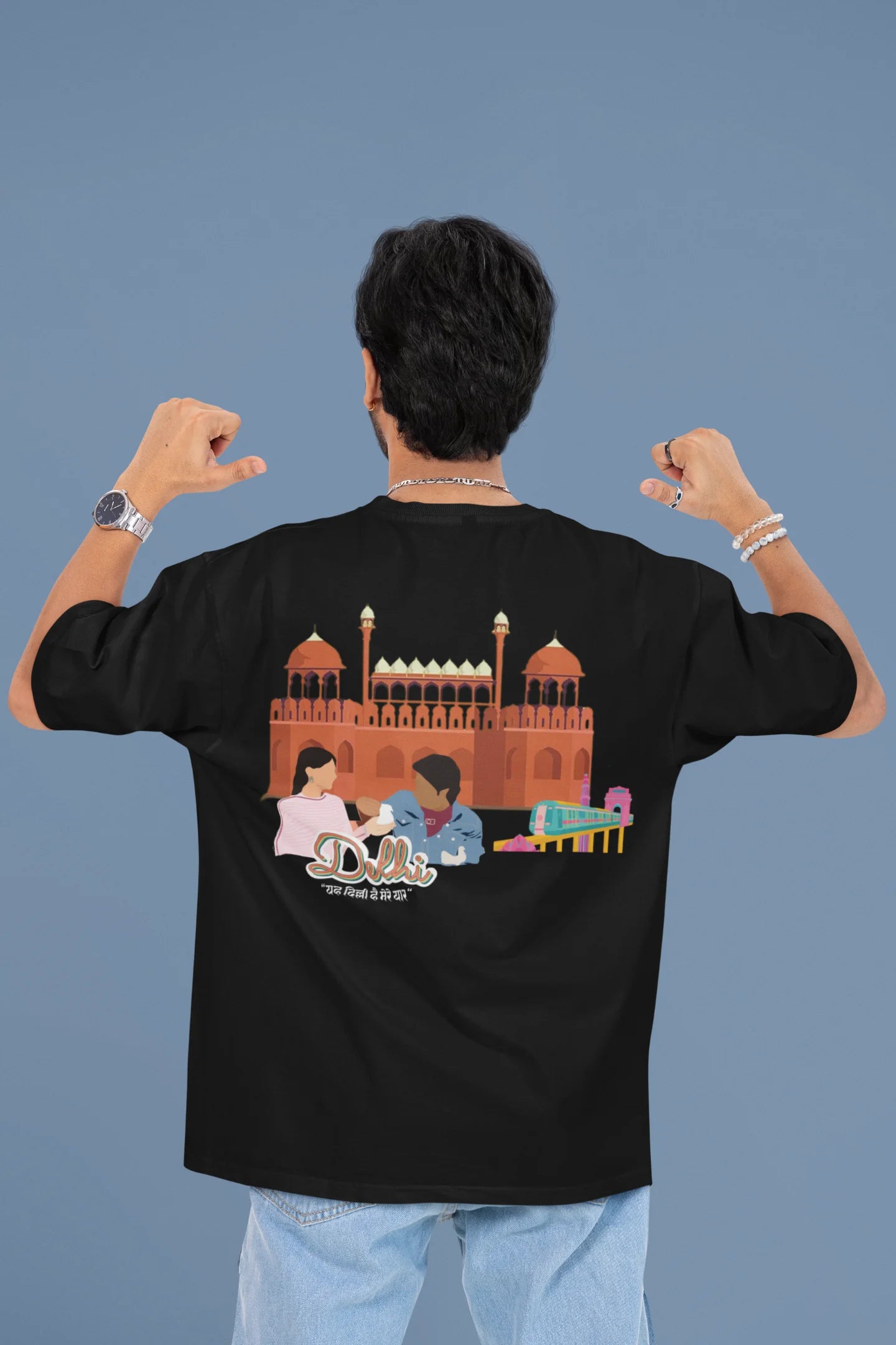 Back view of a male model wearing a black oversized t-shirt featuring a design incorporating the Red Fort and elements representing the city of Delhi, inspired by the Hindi film Delhi 6.
