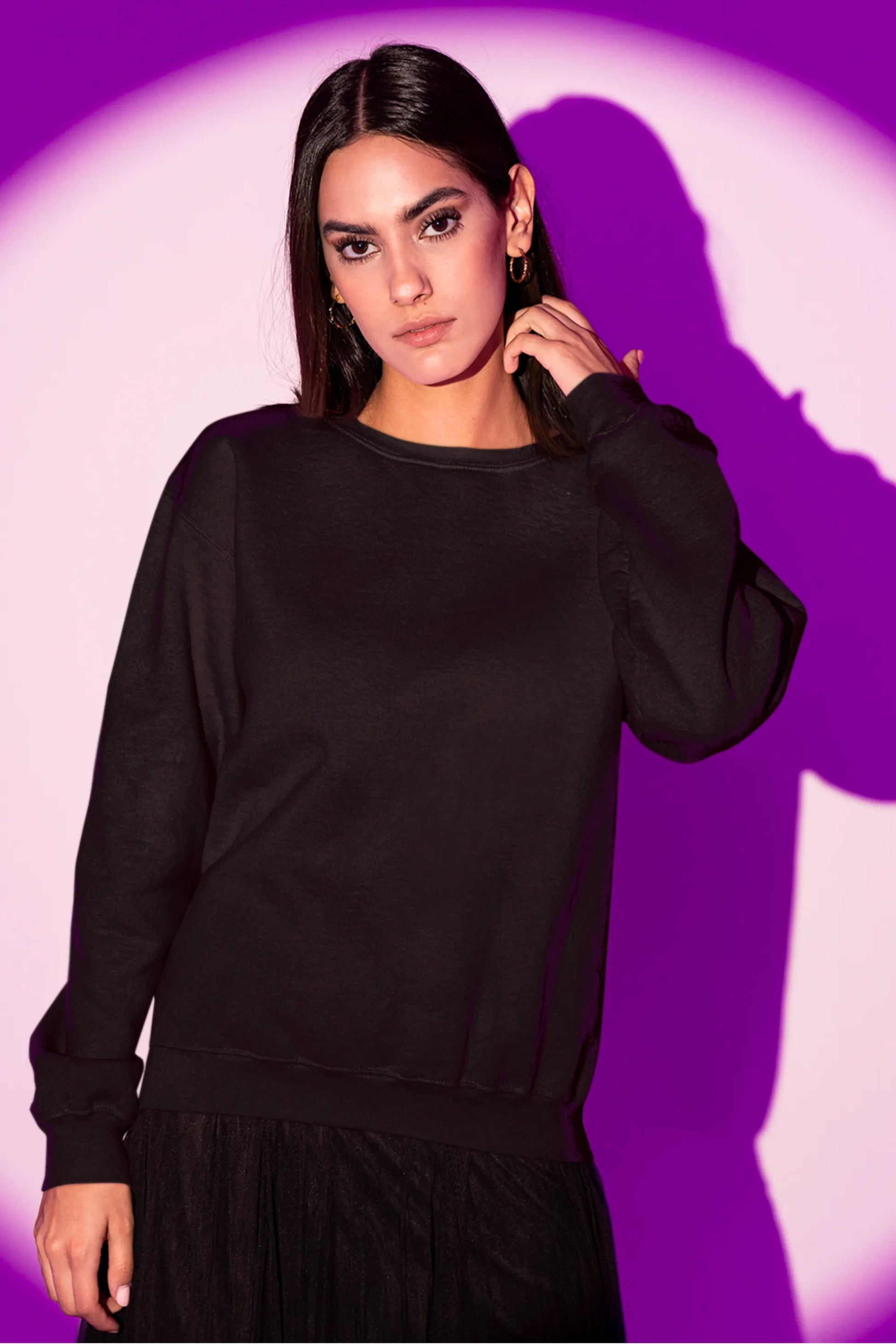 Front view of a female model wearing an cream sweatshirt featuring a detailed illustration of a gray wolf howling at a full moon in a nighttime setting.