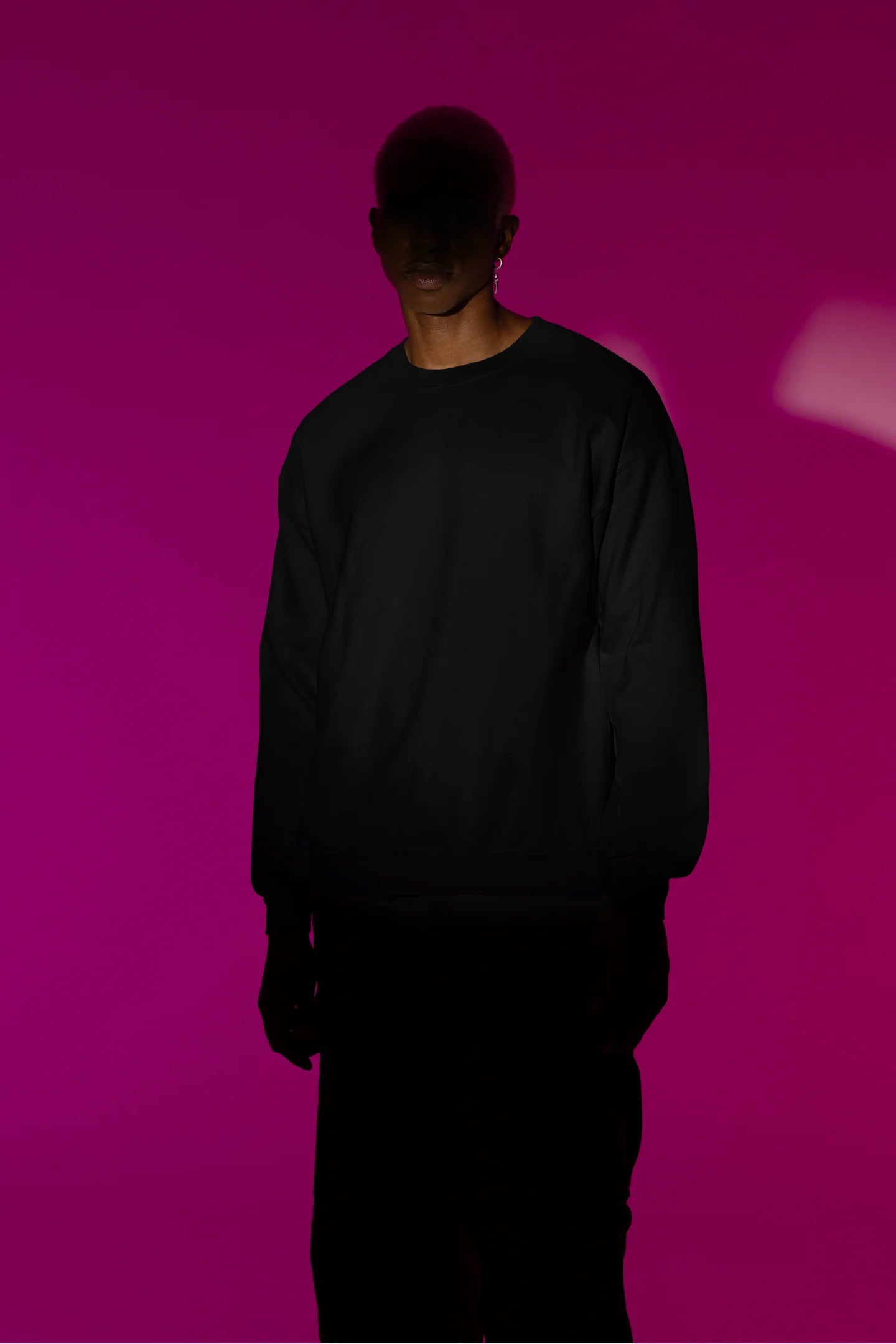 Third front view of male model wearing a black sweatshirt with a design of a cat dressed as a samurai, standing against a backdrop of waves and a rising sun.
