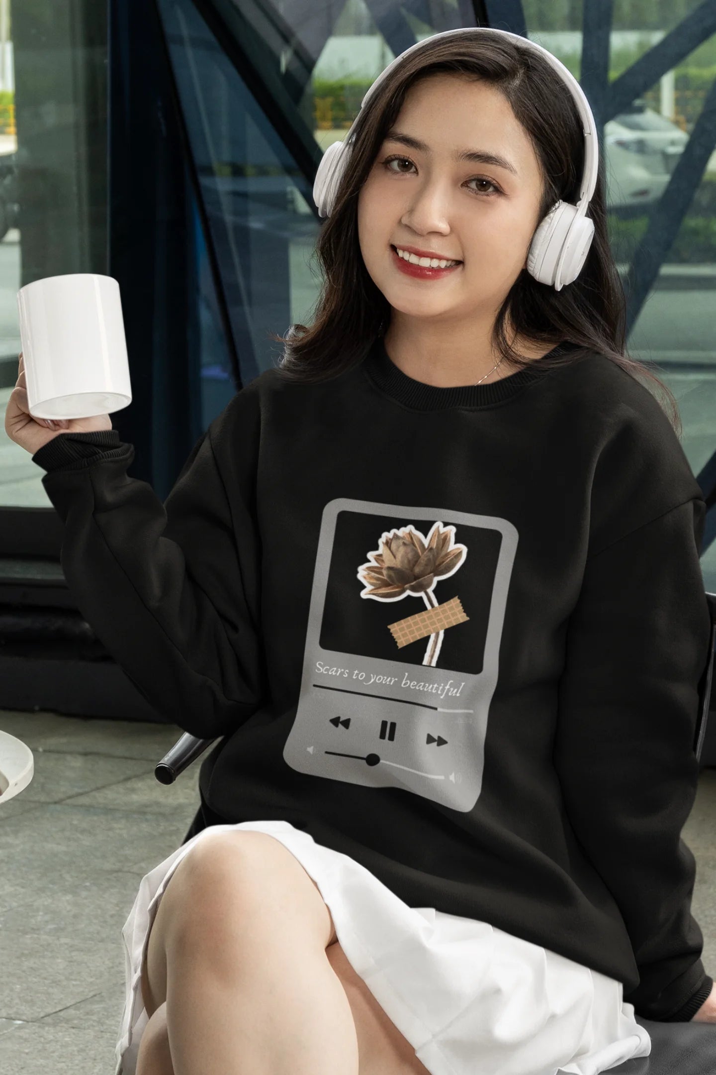 4th front view of a female model wearing a black sweatshirt featuring a design inspired by Alessia Cara's song "Scars to Your Beautiful." The design includes flowers and a message of self-love. Ideal for fans of Alessia Cara and those who appreciate messages of empowerment.