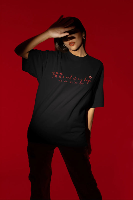 First front view of a female model wearing a black oversized t-shirt with a heart design and the text "All My Love".