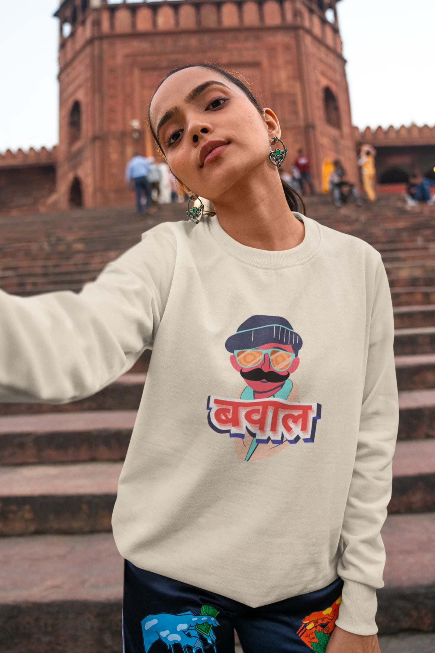 2nd front view of a female model wearing a cream oversized t-shirt with "Bawaal" in a stylish Hindi.
