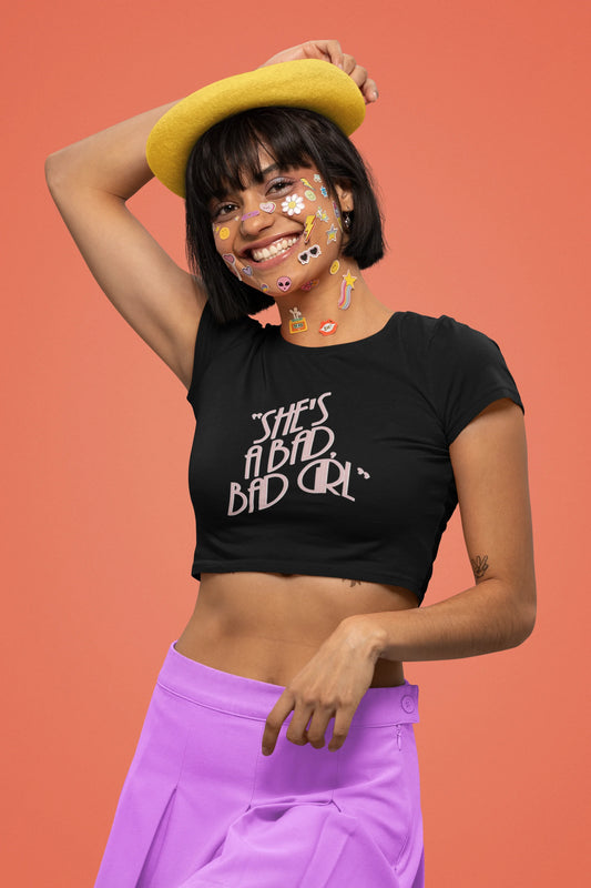 Second front view of a female model wearing a black crop top with "She's a bad bad girl" text, perfect for Swifties and Eras Tour fans.