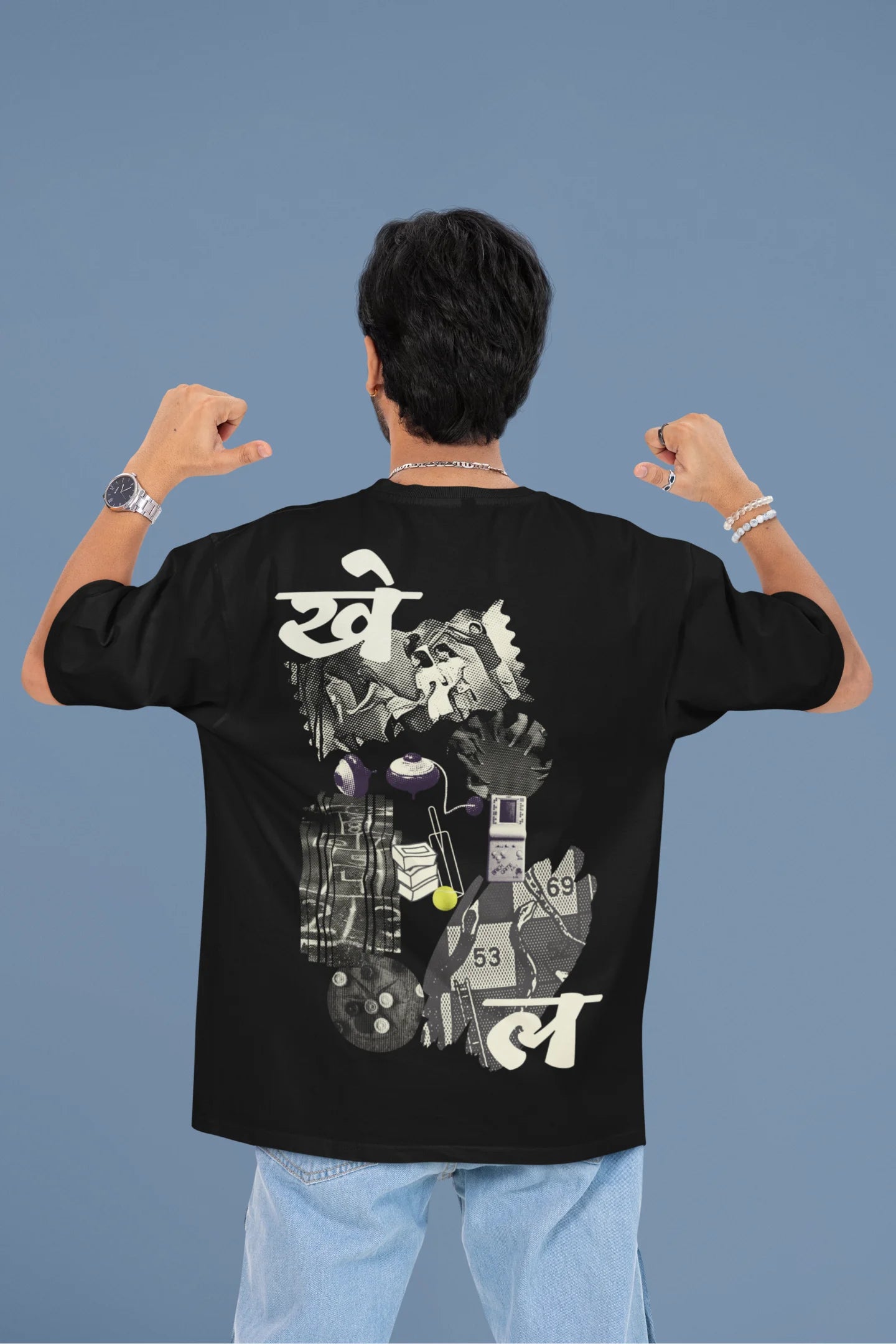 Back view of a male model wearing a black oversized t-shirt featuring a collage of illustrations or symbols representing various childhood games commonly played by kids in India.