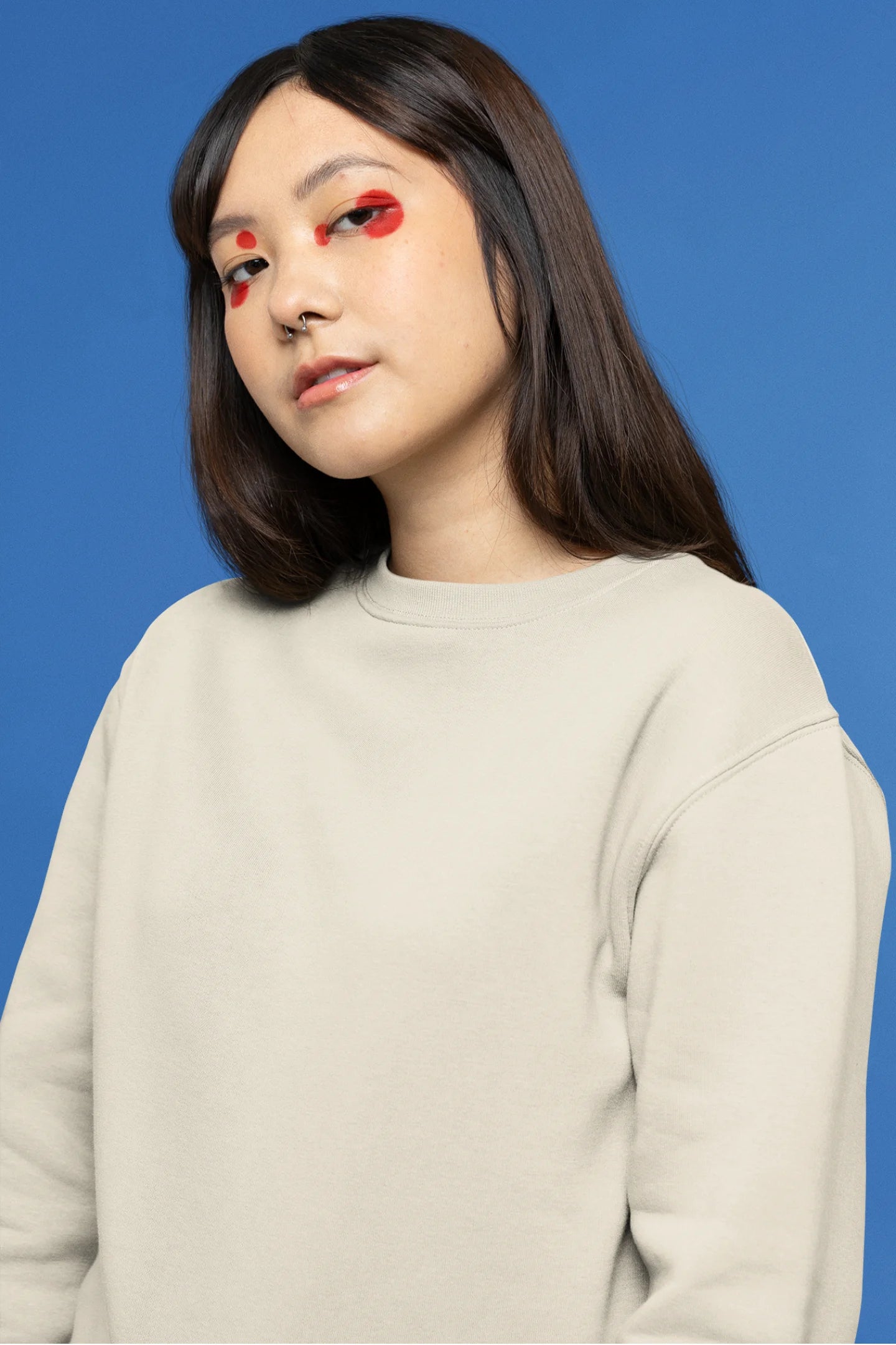 Second front view of female model wearing a cream sweatshirt with a design of a cat dressed as a samurai, standing against a backdrop of waves and a rising sun.