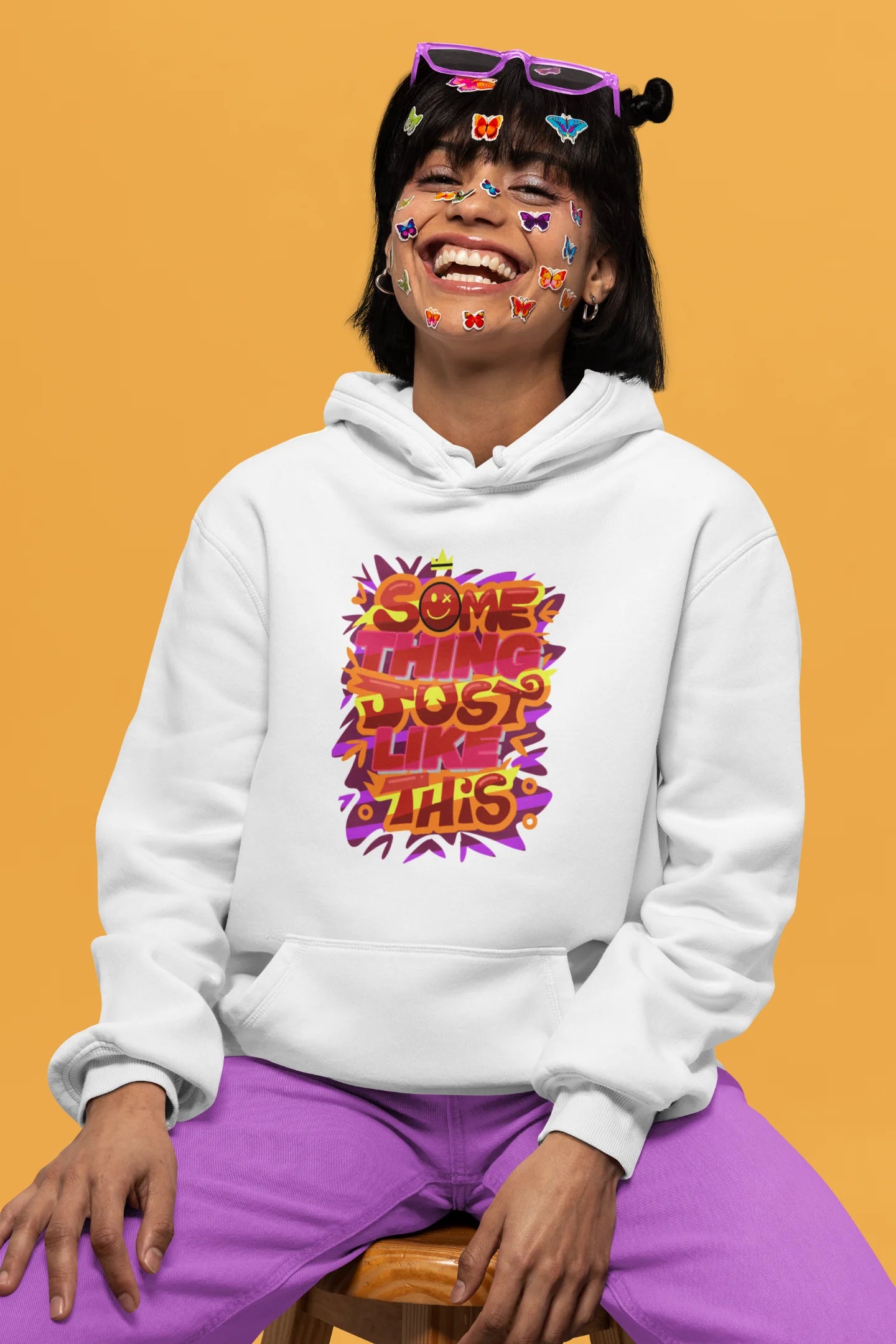 Third front view of a female model wearing an off-white hoodie featuring the designs inspired from Coldplay's "Something Just Like This" music video.