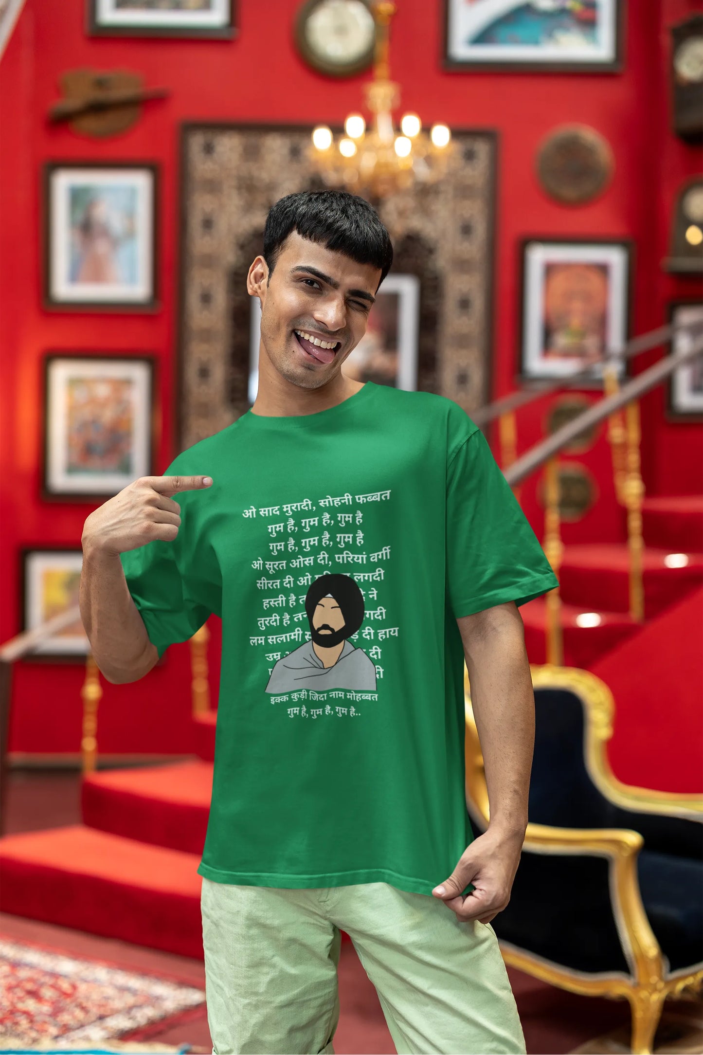 Third front view of a male model wearing a forest green oversized T-shirt with a Diljit Dosanjh portrait with lyrics from the song "Ikk Kudi" in the background.