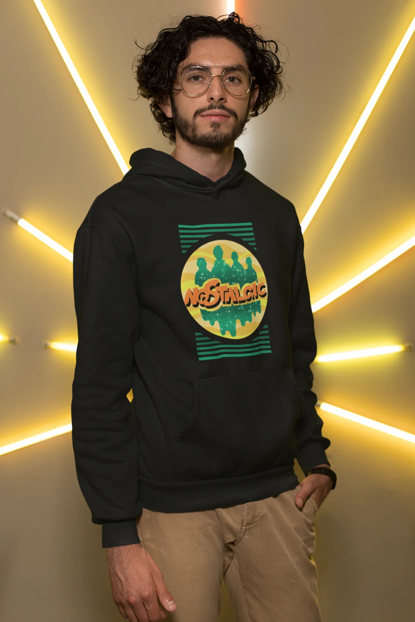 First front view of a male model wearing an black hoodie with a shadow silhouette of the Coldplay band members and the word "Nostalgic" printed on it.