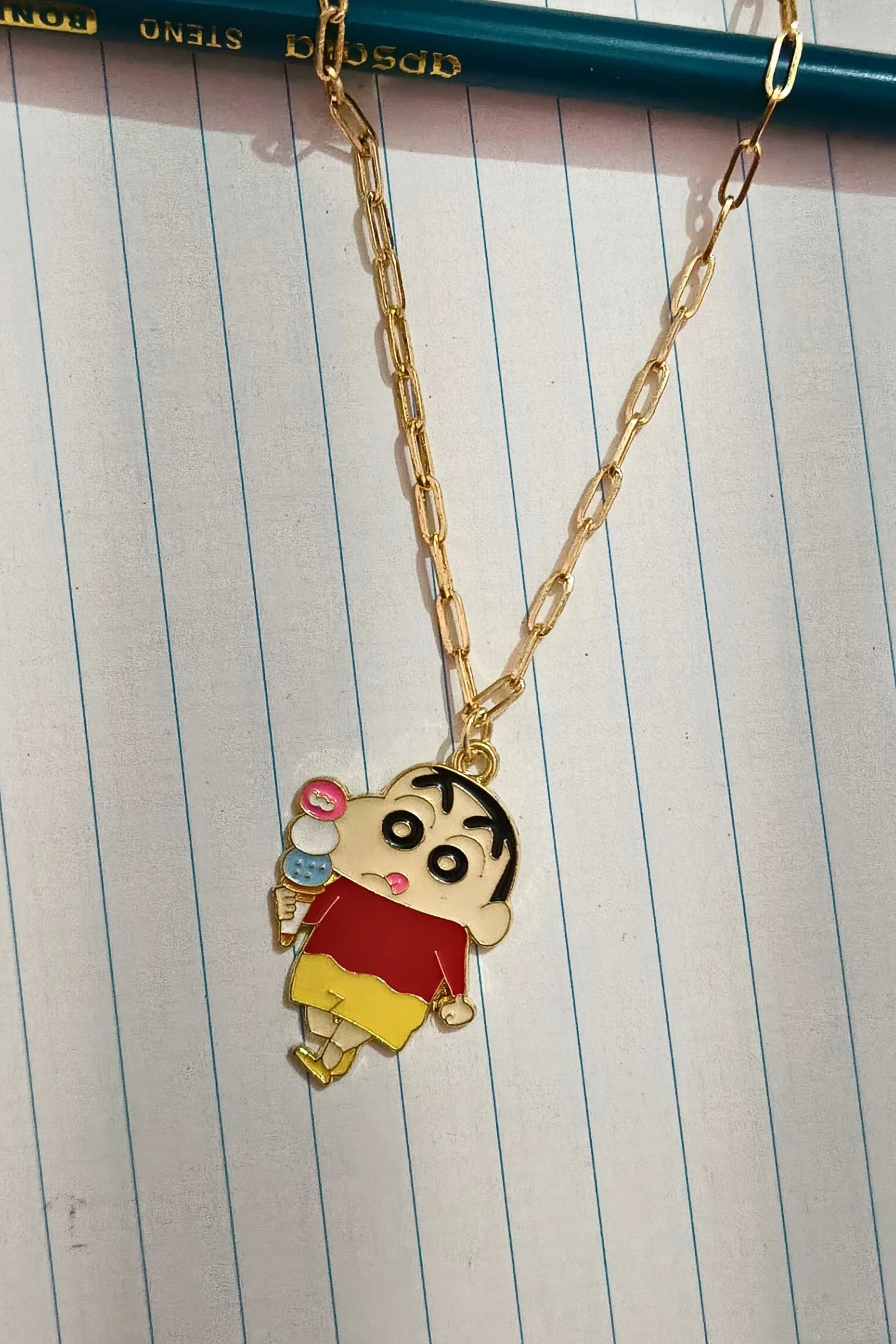 2nd view of a gold chain necklace with a small pendant depicting Shin Chan eating ice cream.