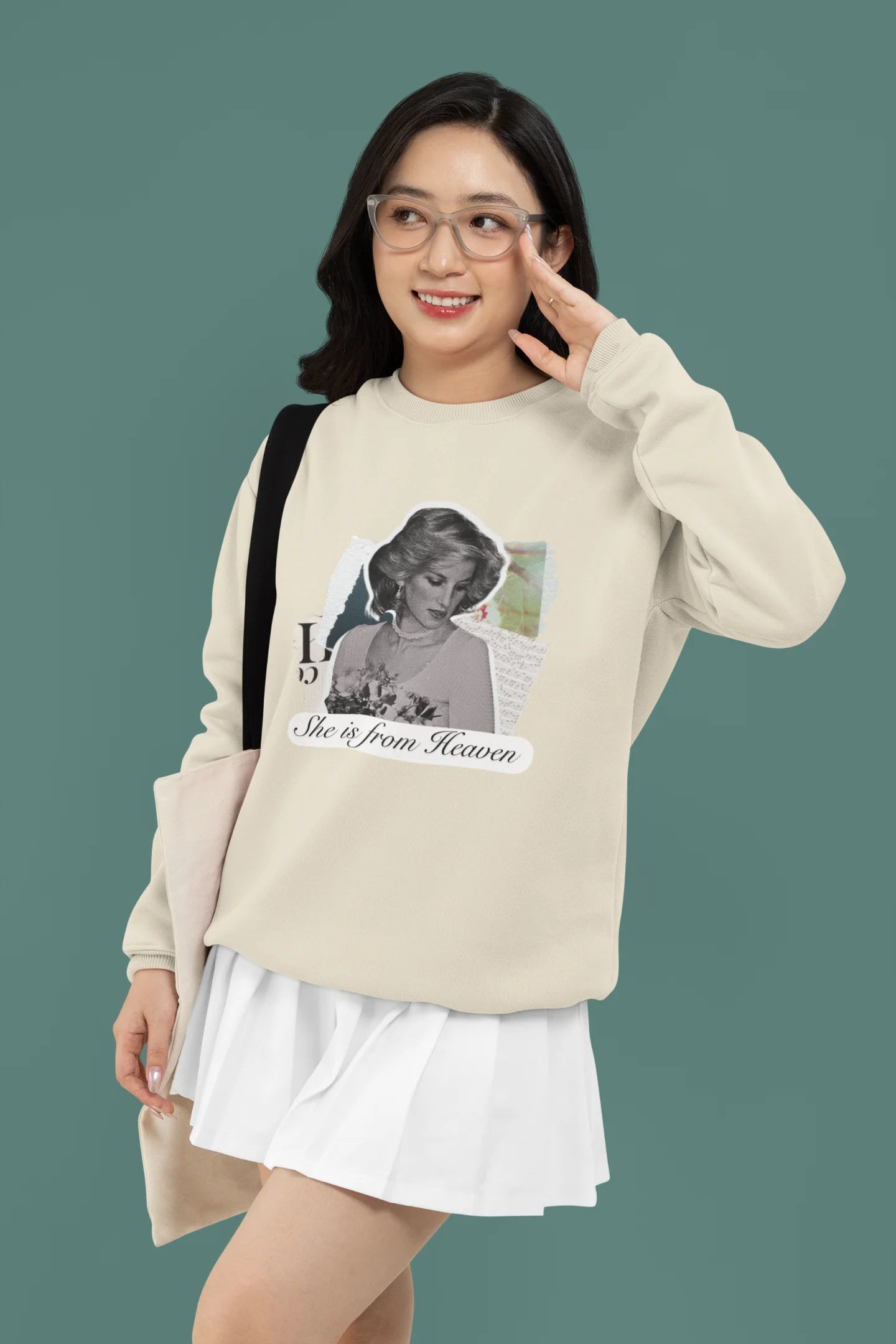 2nd front view of female model wearing a cream sweatshirt featuring a black and white photo of Princess Diana with the text "She is from Heaven." Ideal for fans of Princess Diana and those who want to celebrate a royal icon.