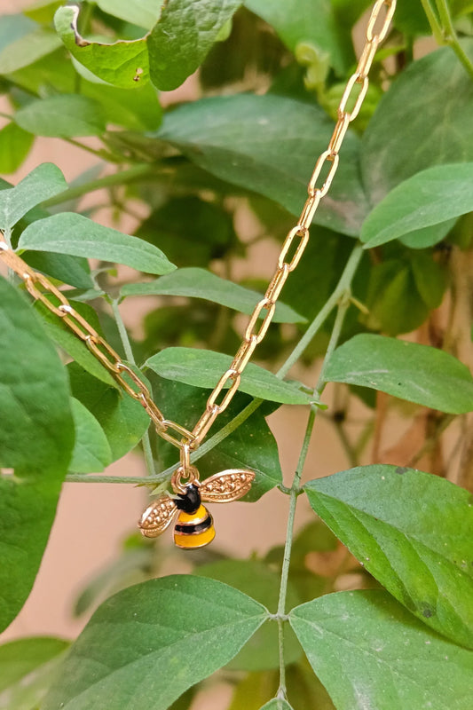 First view of a gold chain necklace with a small pendant shaped like a honey bee.