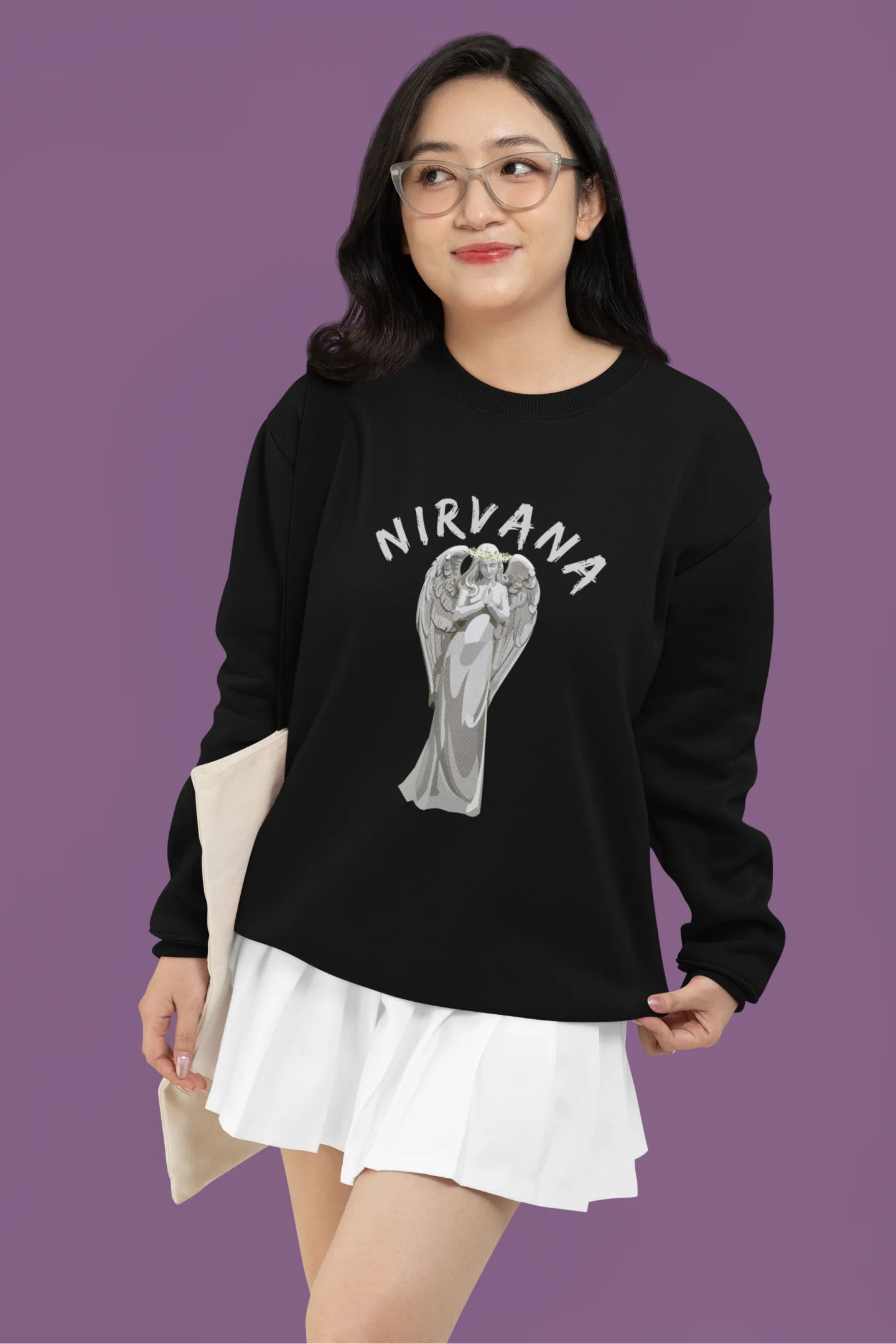 First front image of female model wearing a black sweatshirt featuring a design of a winged angel with the text "Nirvana" above it. Ideal for fans of Nirvana and those who love grunge aesthetics.