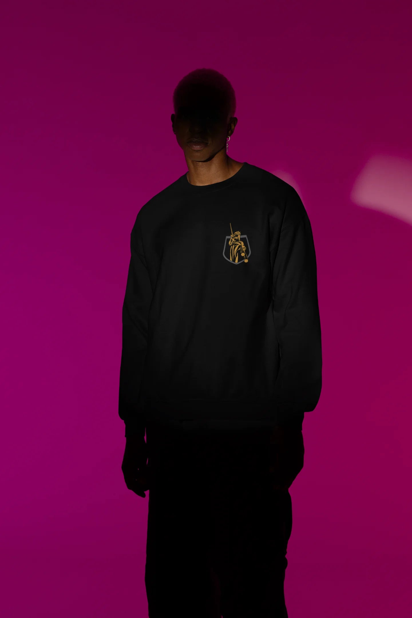 First front view of a male model wearing a black sweatshirt with a brutalist Lady Justice statue design.