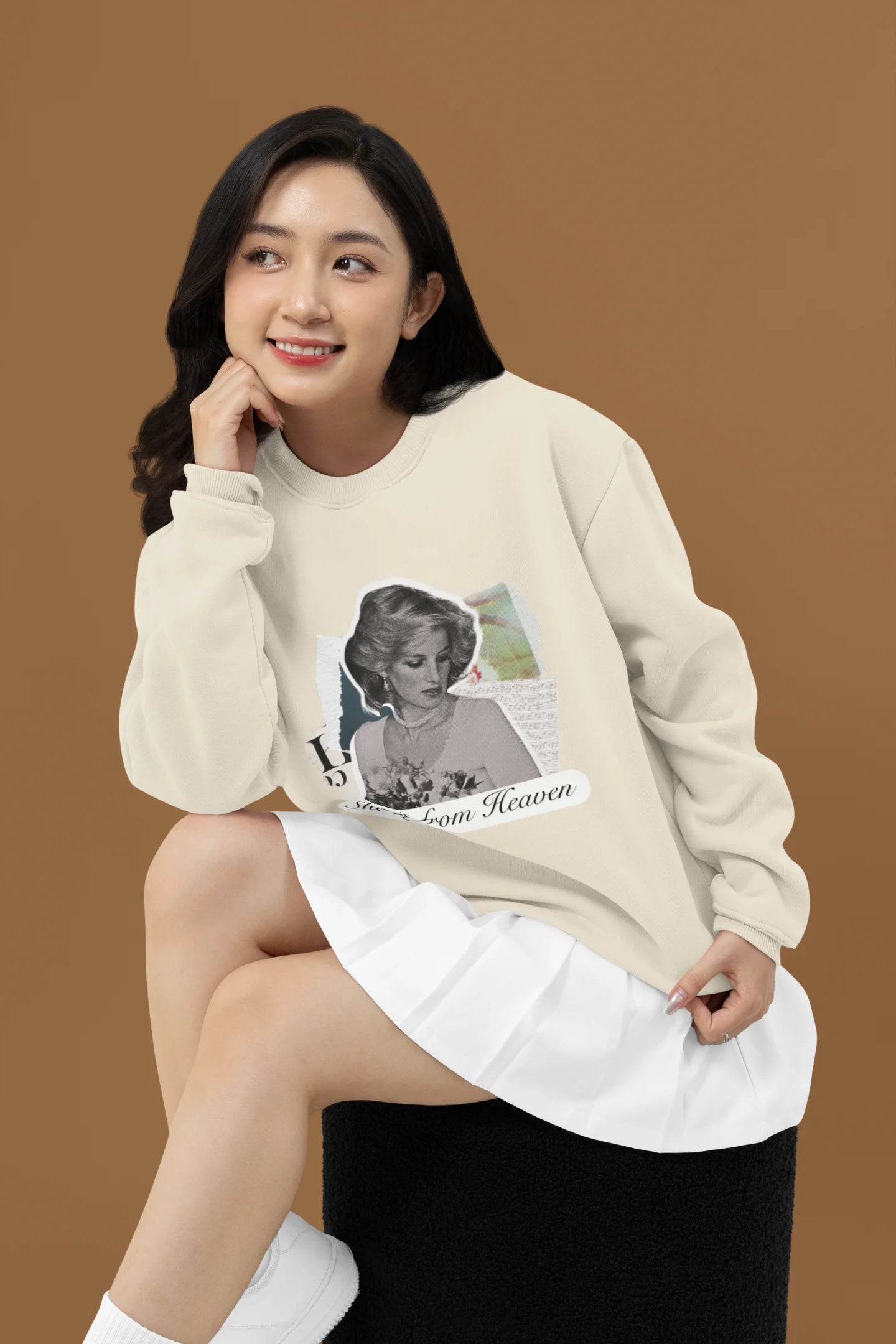 3rd front view of female model wearing a cream sweatshirt featuring a black and white photo of Princess Diana with the text "She is from Heaven." Ideal for fans of Princess Diana and those who want to celebrate a royal icon.