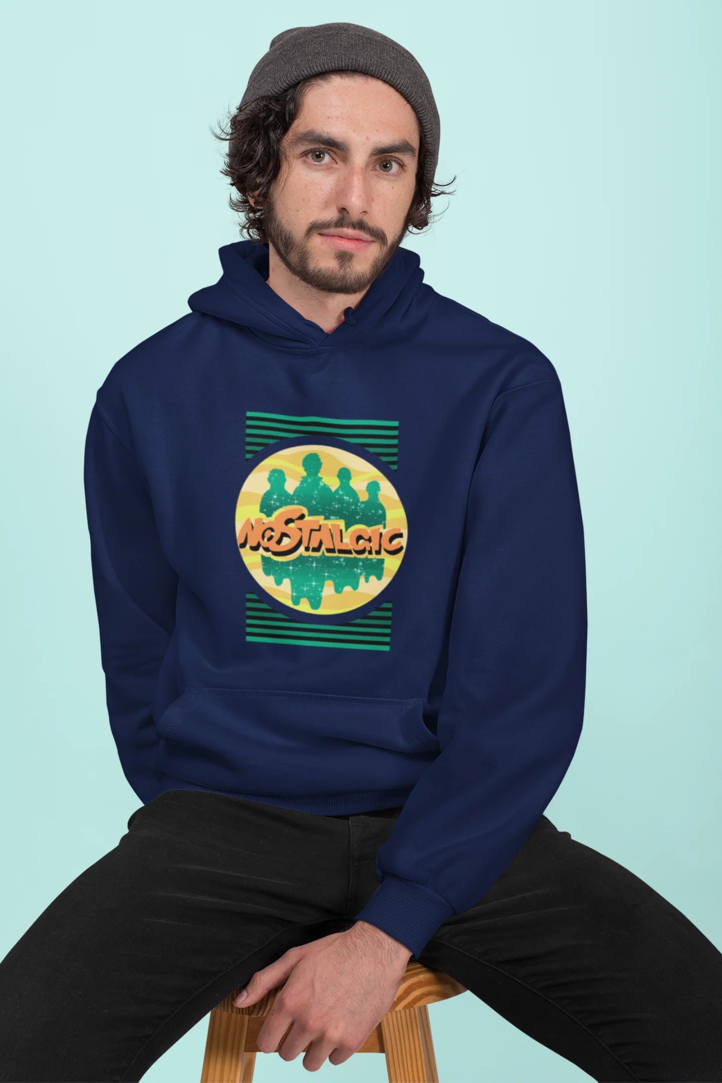 First front view of a male model wearing an navy blue hoodie with a shadow silhouette of the Coldplay band members and the word "Nostalgic" printed on it.