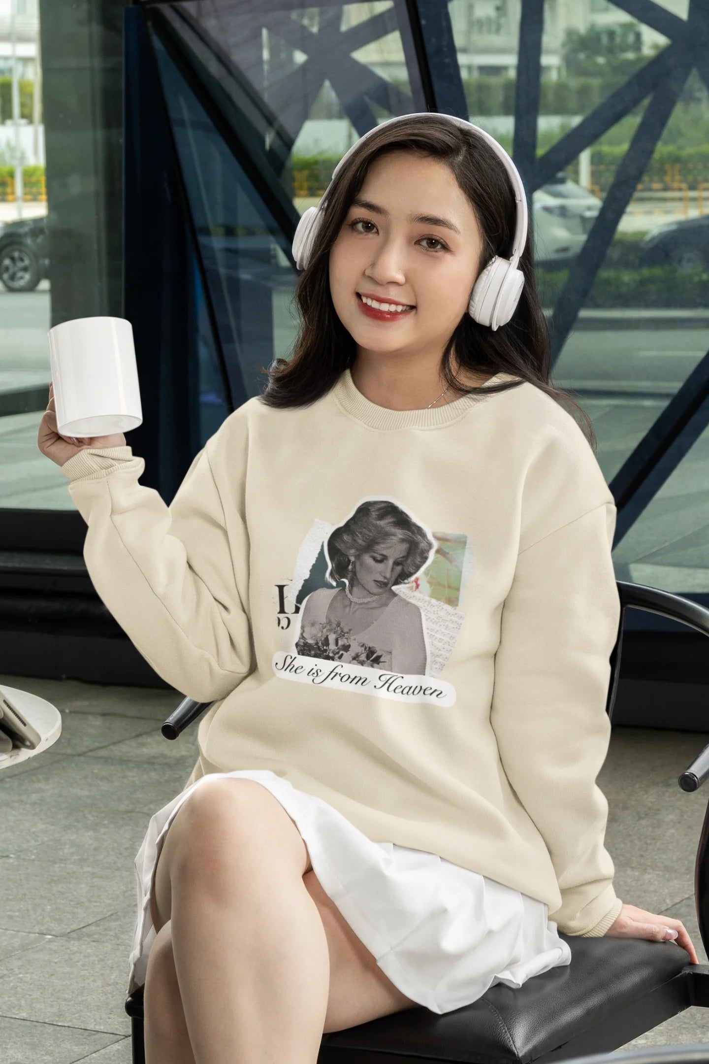 First front view of female model wearing a cream sweatshirt featuring a black and white photo of Princess Diana with the text "She is from Heaven." Ideal for fans of Princess Diana and those who want to celebrate a royal icon.