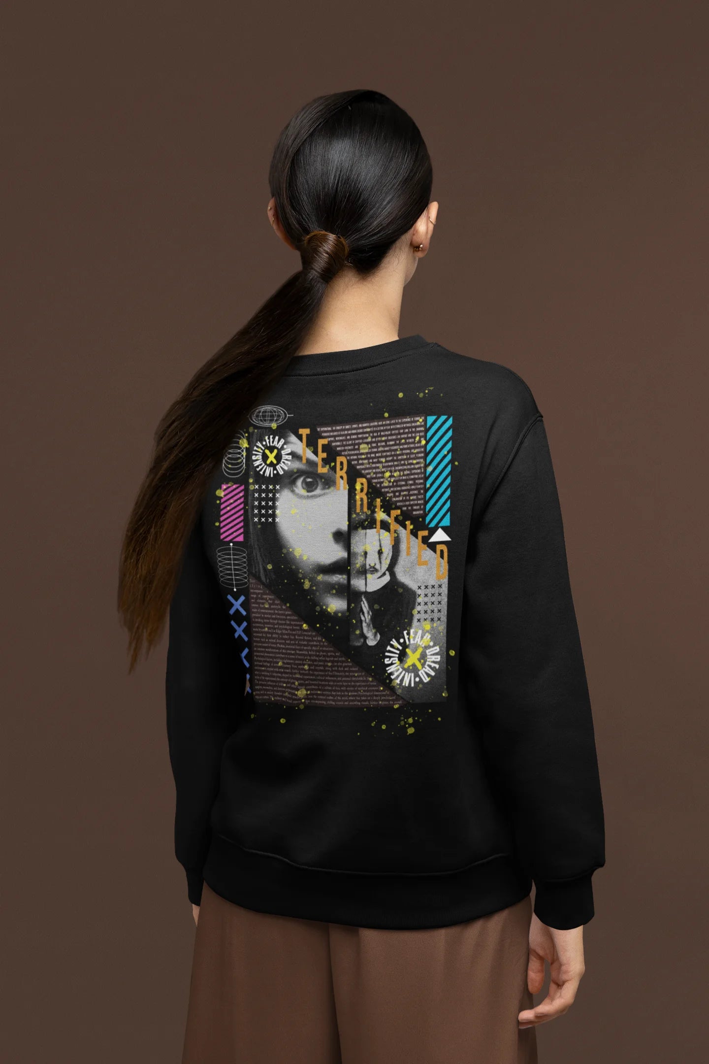 Back view of a female model wearing a black brutalist-inspired sweatshirt featuring an abstract depiction of terrified people in a stylized font.