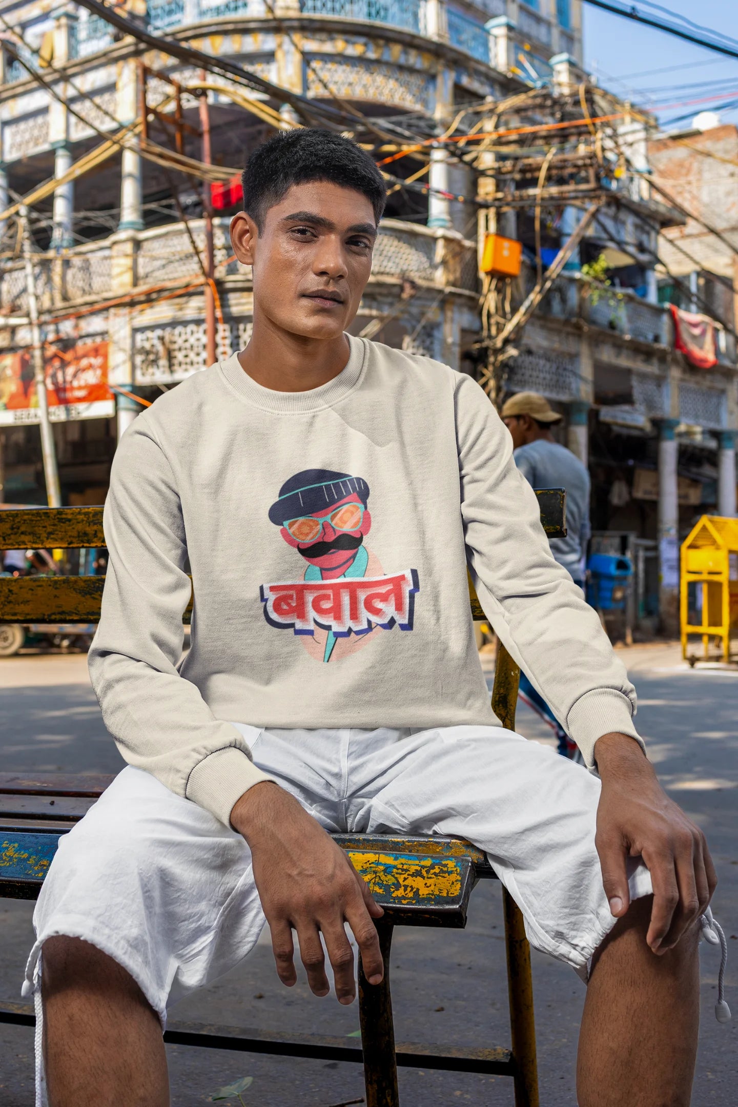 4th front view of a male model wearing a cream oversized t-shirt with "Bawaal" in a stylish Hindi.