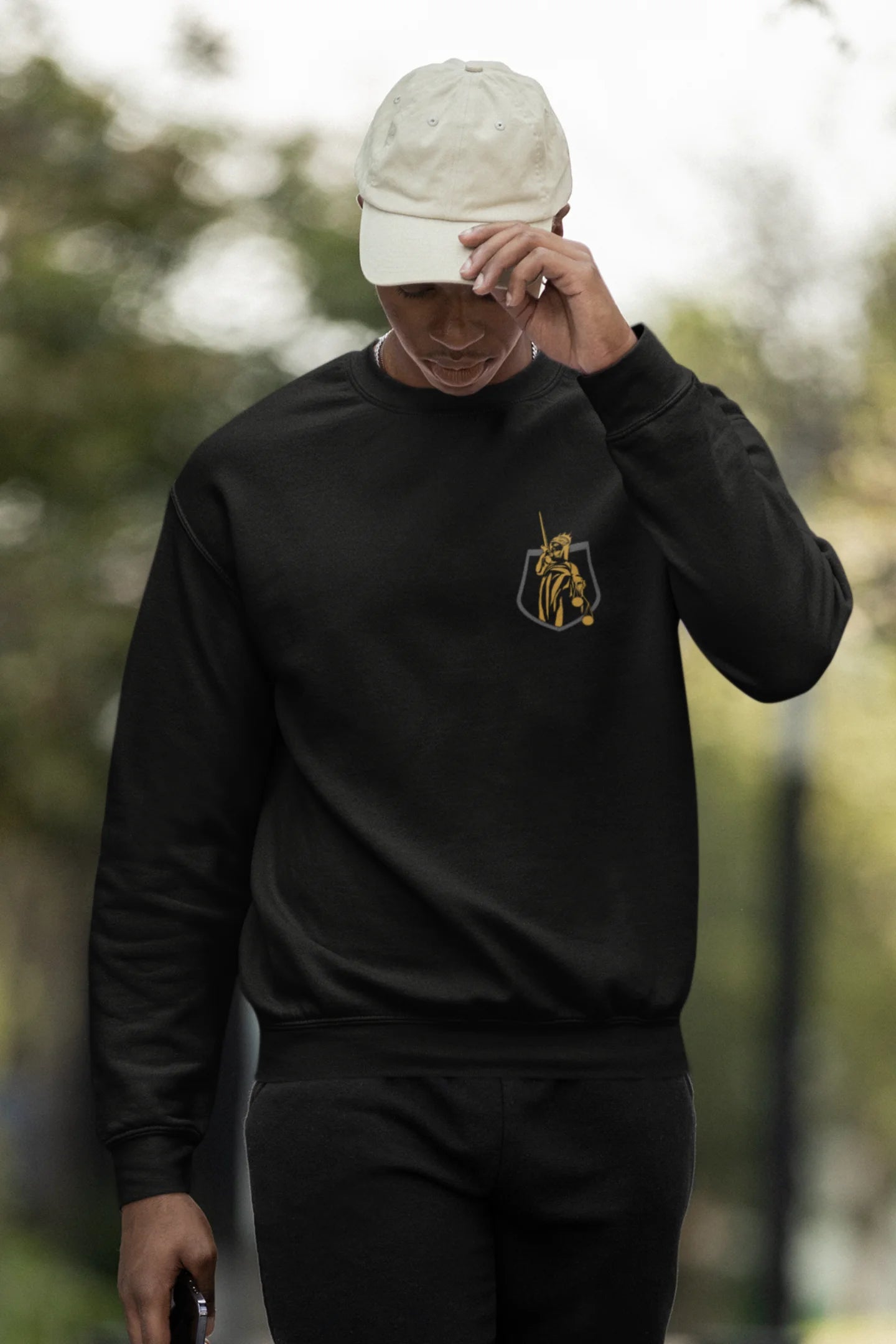 Second front view of a male model wearing a black sweatshirt with a brutalist Lady Justice statue design.
