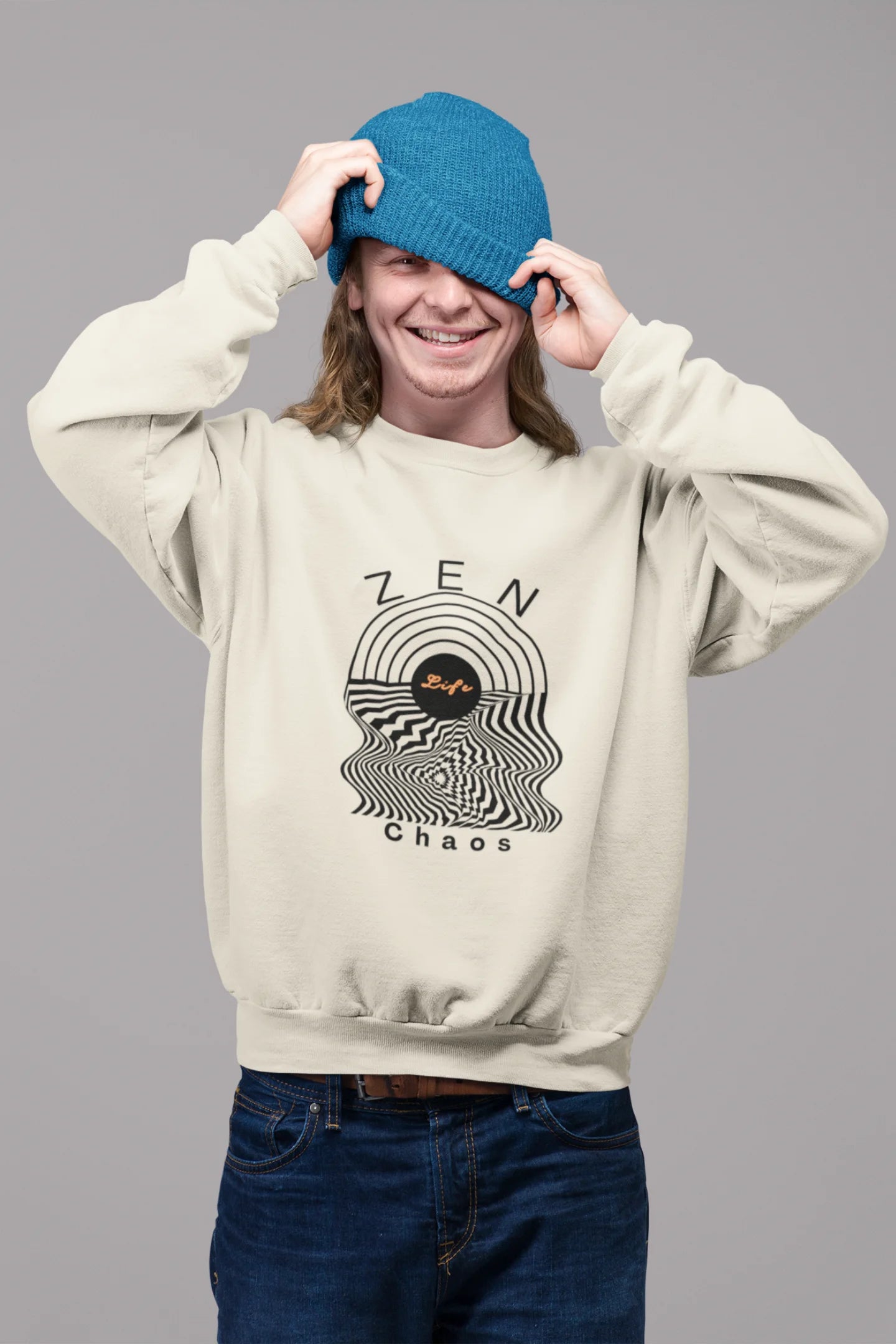 First front view of a male model wearing an cream sweatshirt featuring an aesthetic design of a setting sun and crashing waves with the text "Zen & Chaos" above it. Ideal for those who love philosophical themes and visually striking clothing.