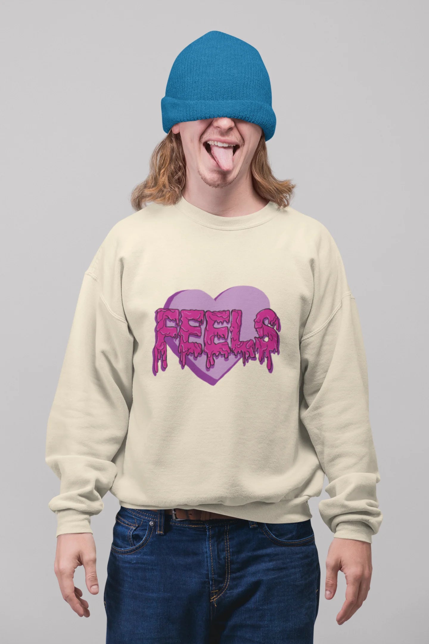 2nd front view of a male model wearing a cream sweatshirt featuring a heart with melting "Feels" text.