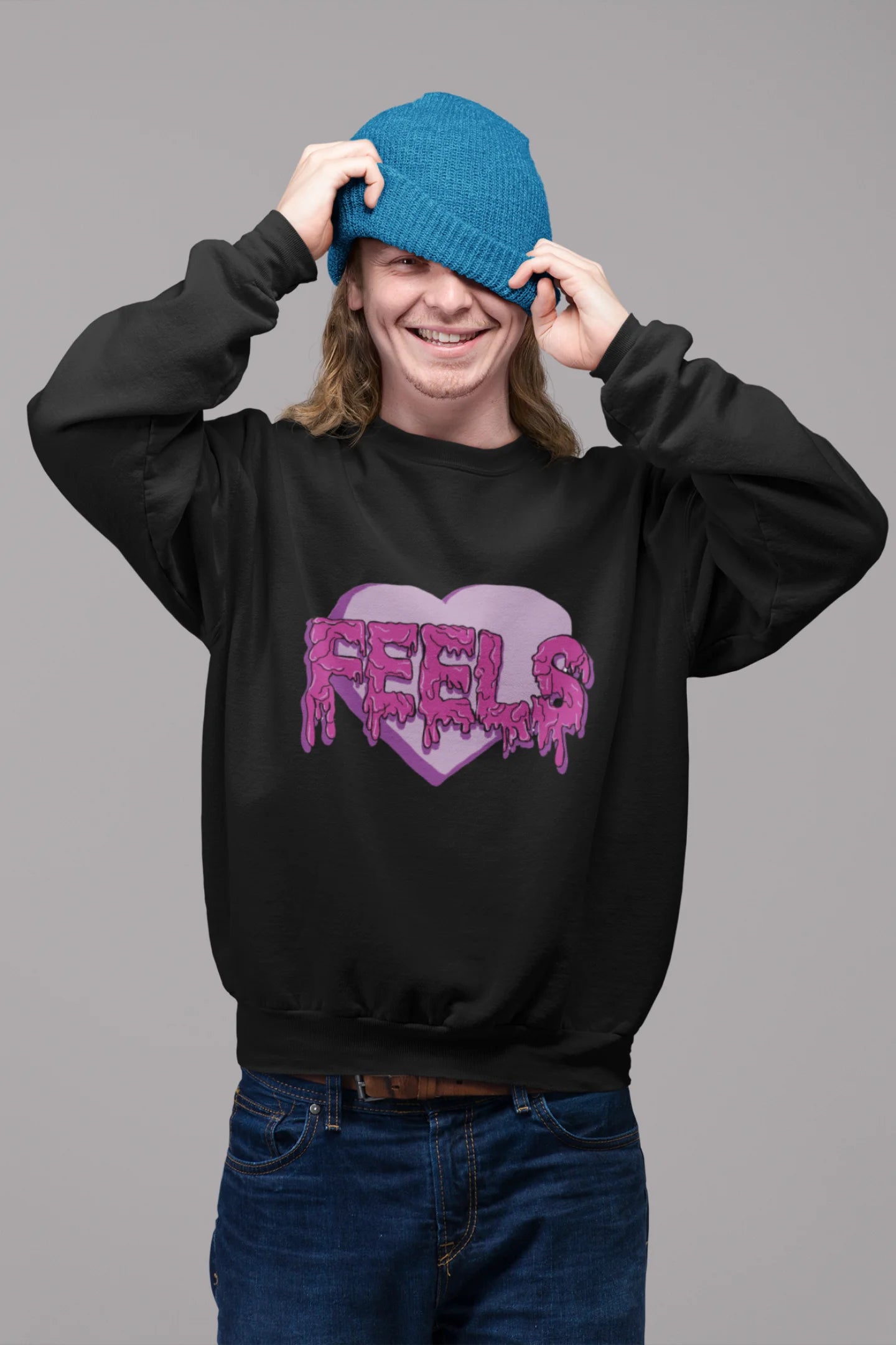 First front view of a male model wearing a black sweatshirt featuring a heart with melting "Feels" text.