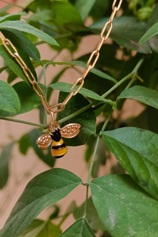 2nd view of a gold chain necklace with a small pendant shaped like a honey bee.