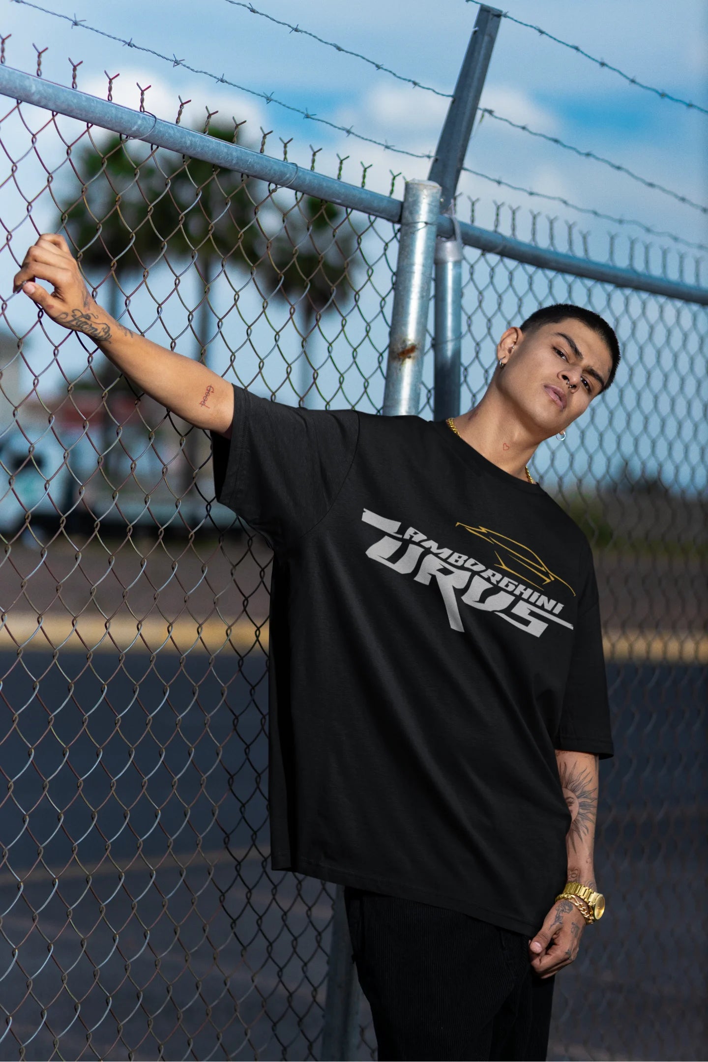 2nd front view of a male model wearing a black oversized t-shirt featuring a design of a Lamborghini Urus.