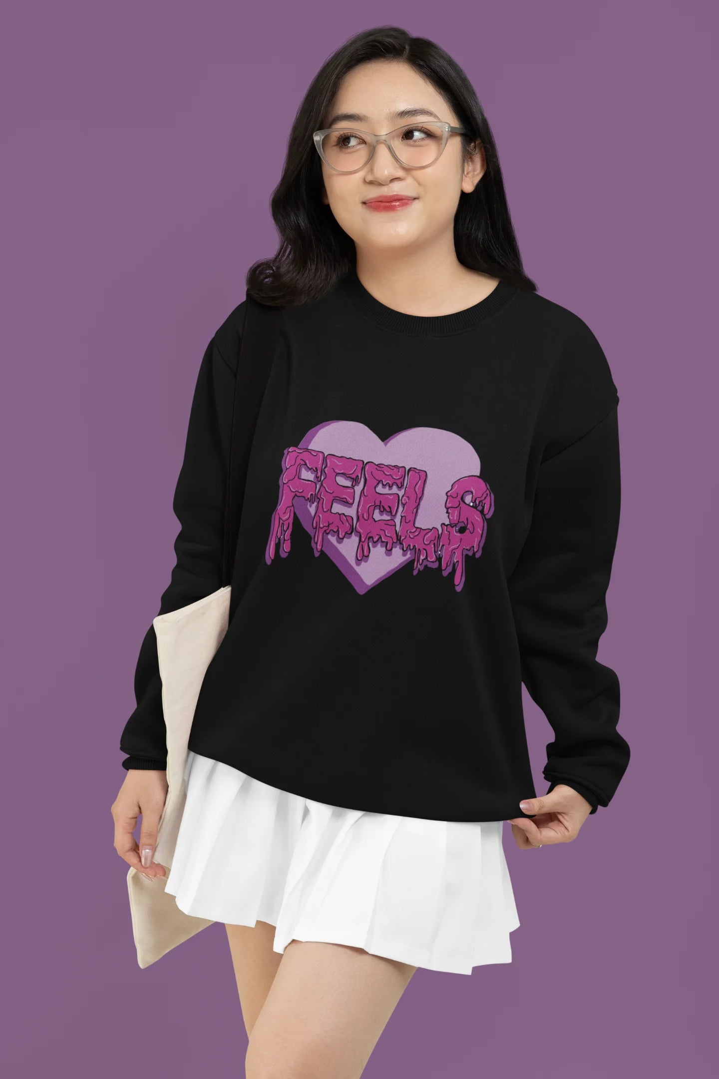 2nd front view of a female model wearing a black sweatshirt featuring a heart with melting "Feels" text.