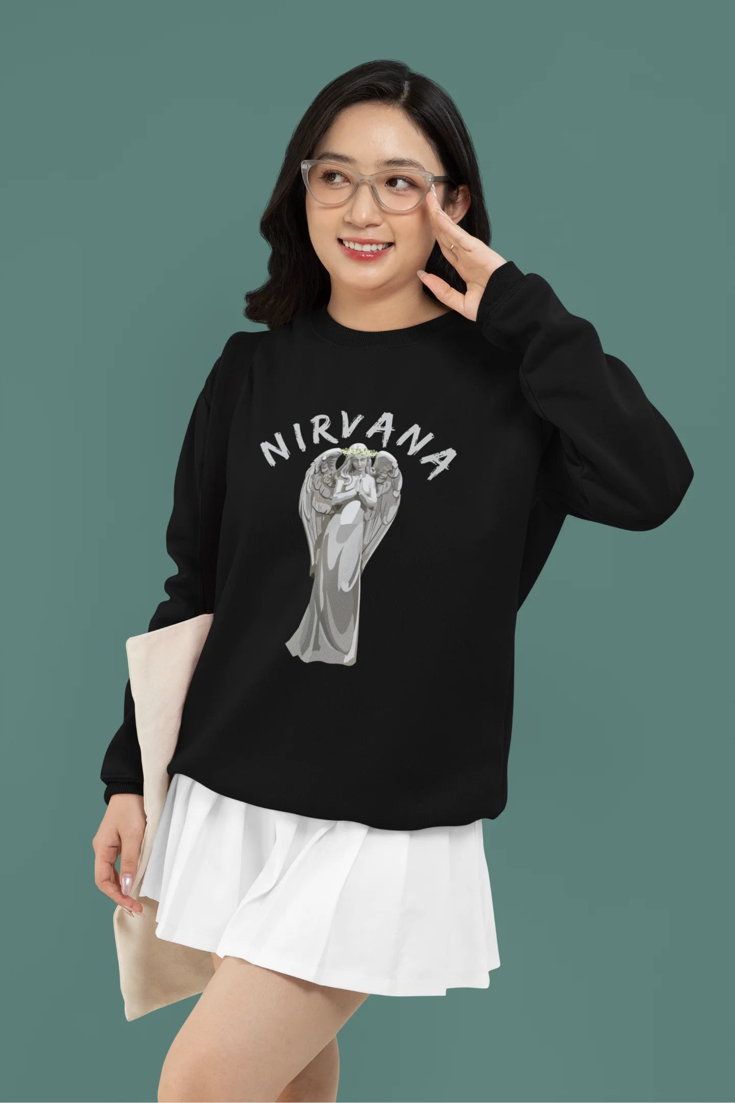 4th front image of female model wearing a black sweatshirt featuring a design of a winged angel with the text "Nirvana" above it. Ideal for fans of Nirvana and those who love grunge aesthetics.
