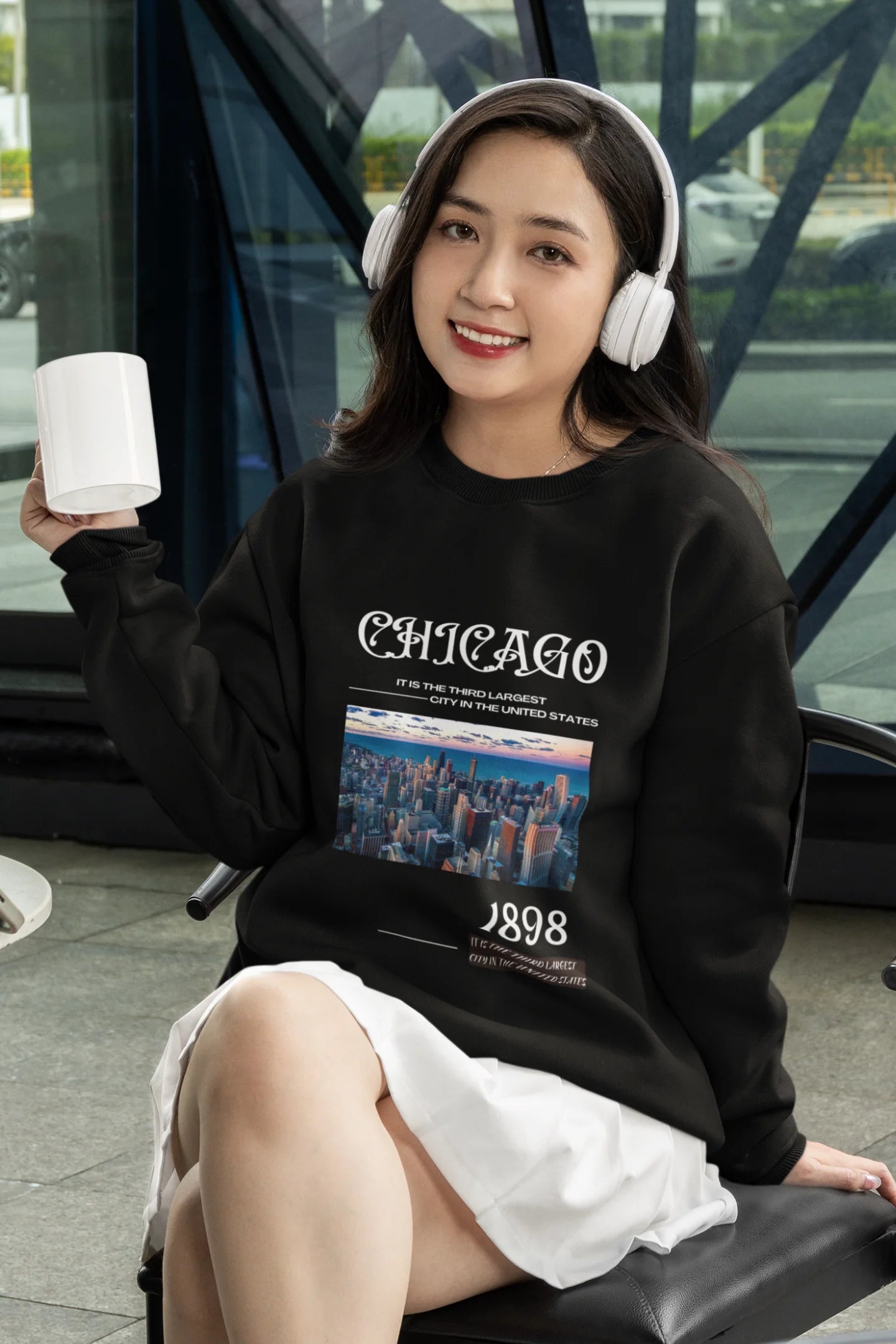 2nd front view of female model wearing a black sweatshirt with a Chicago skyline design, offering a relaxed urban aesthetic.