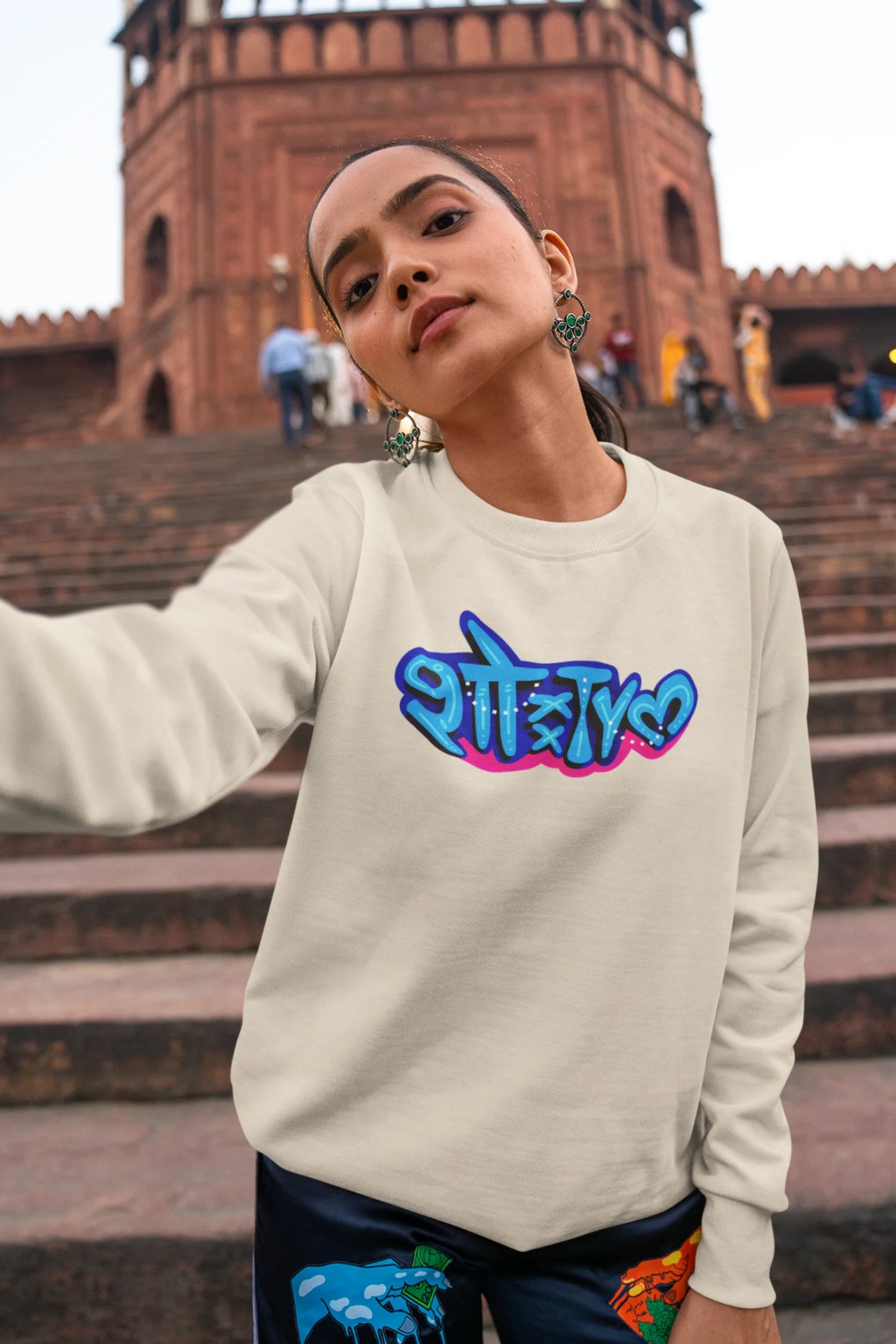First front view of a female model wearing a cream oversized t-shirt featuring "Showtime" in Hindi.